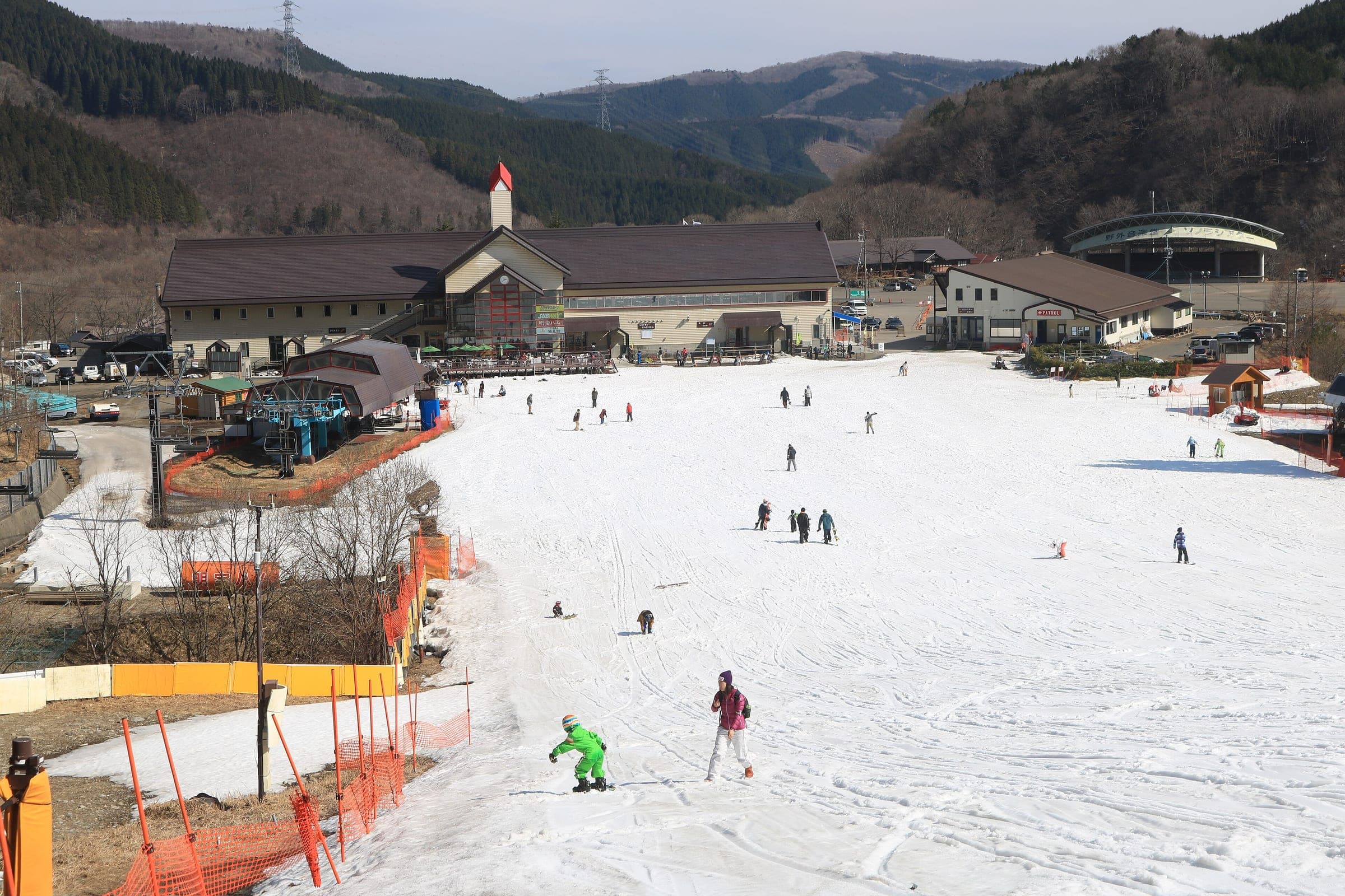 Skiers and snowboarders ride down to the base lodge at Meiho Snow Resort on a sunny March day