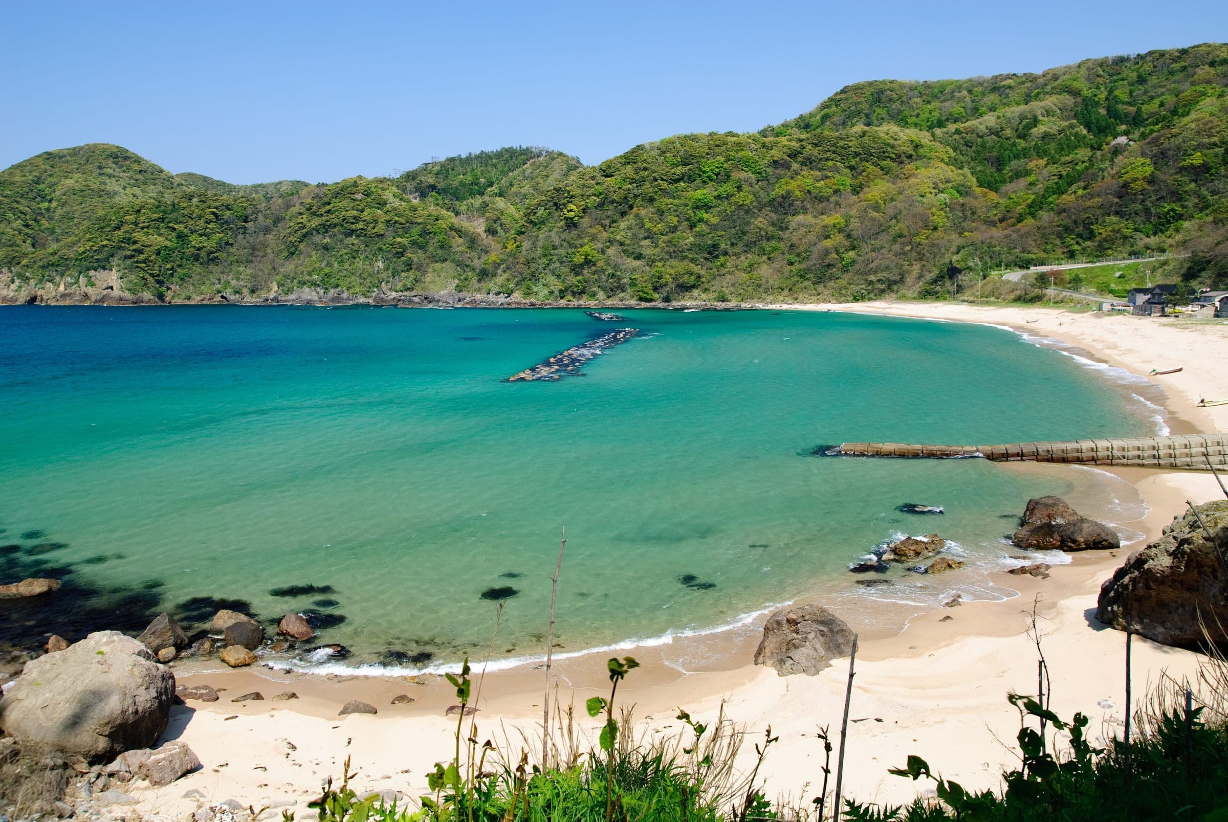 Green hills wrap around the turquoise cove of Yasugihama beach in Kami