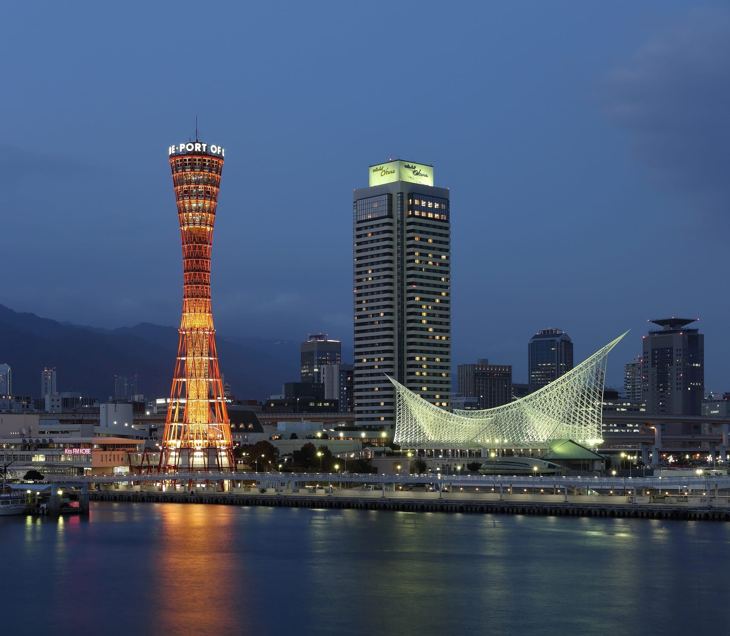 Kobe Port Tower glows red beside the Maritime Museum on the harbour at dusk
