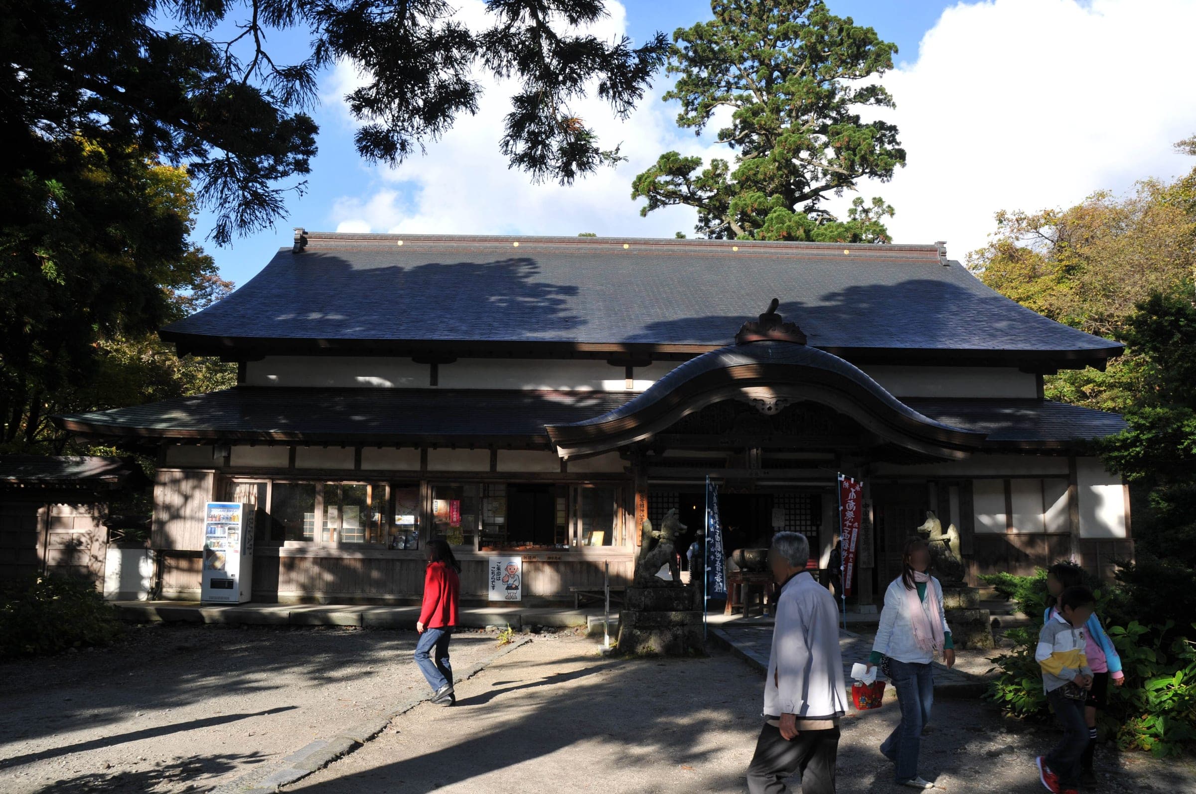 Visitors stand outside the broad tiled hall of Daisen-ji under old cedars in November