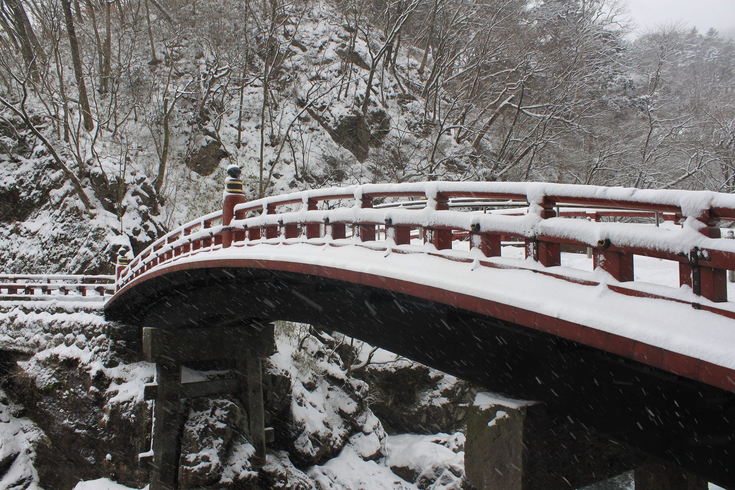 Snow falls on the red lacquered Shinkyo bridge at the entrance to Nikko's shrines