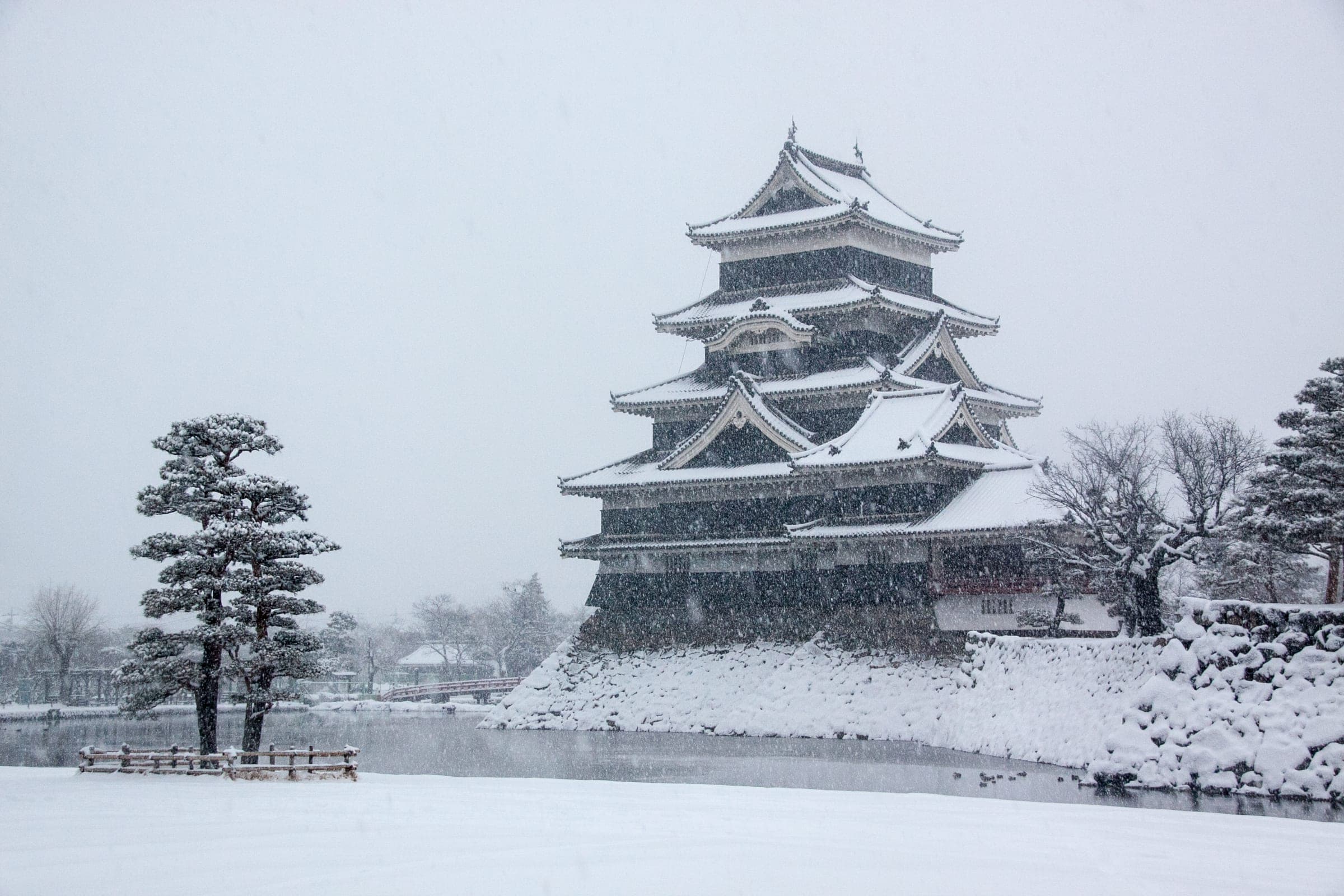 Matsumoto Castle's black keep stands over its moat during a heavy February snowfall.