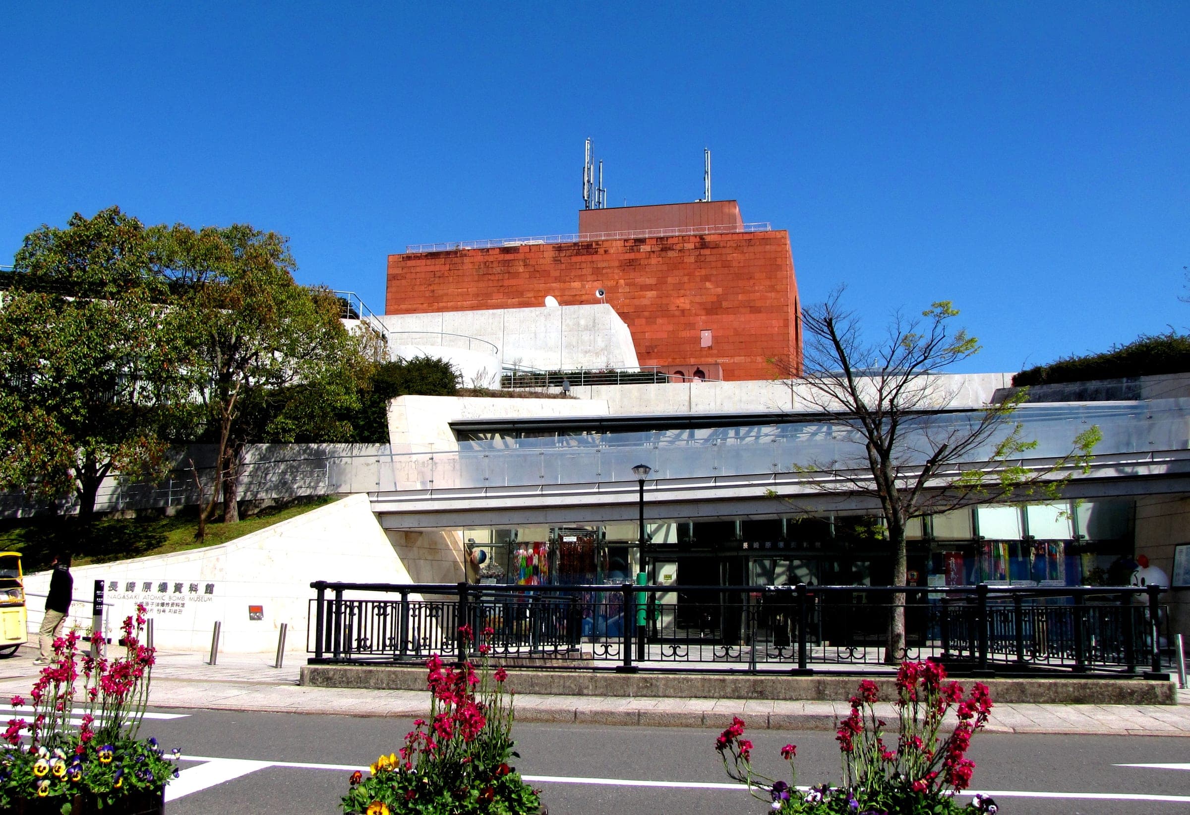 The brick tower and glass entrance hall of the Nagasaki Atomic Bomb Museum sit above the street in spring sun