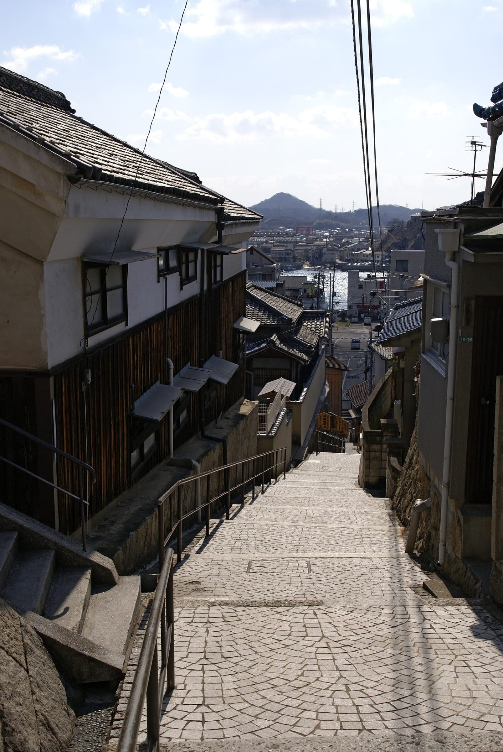 The paved Senkoji Shinmichi steps drop between old houses toward the Onomichi waterfront.