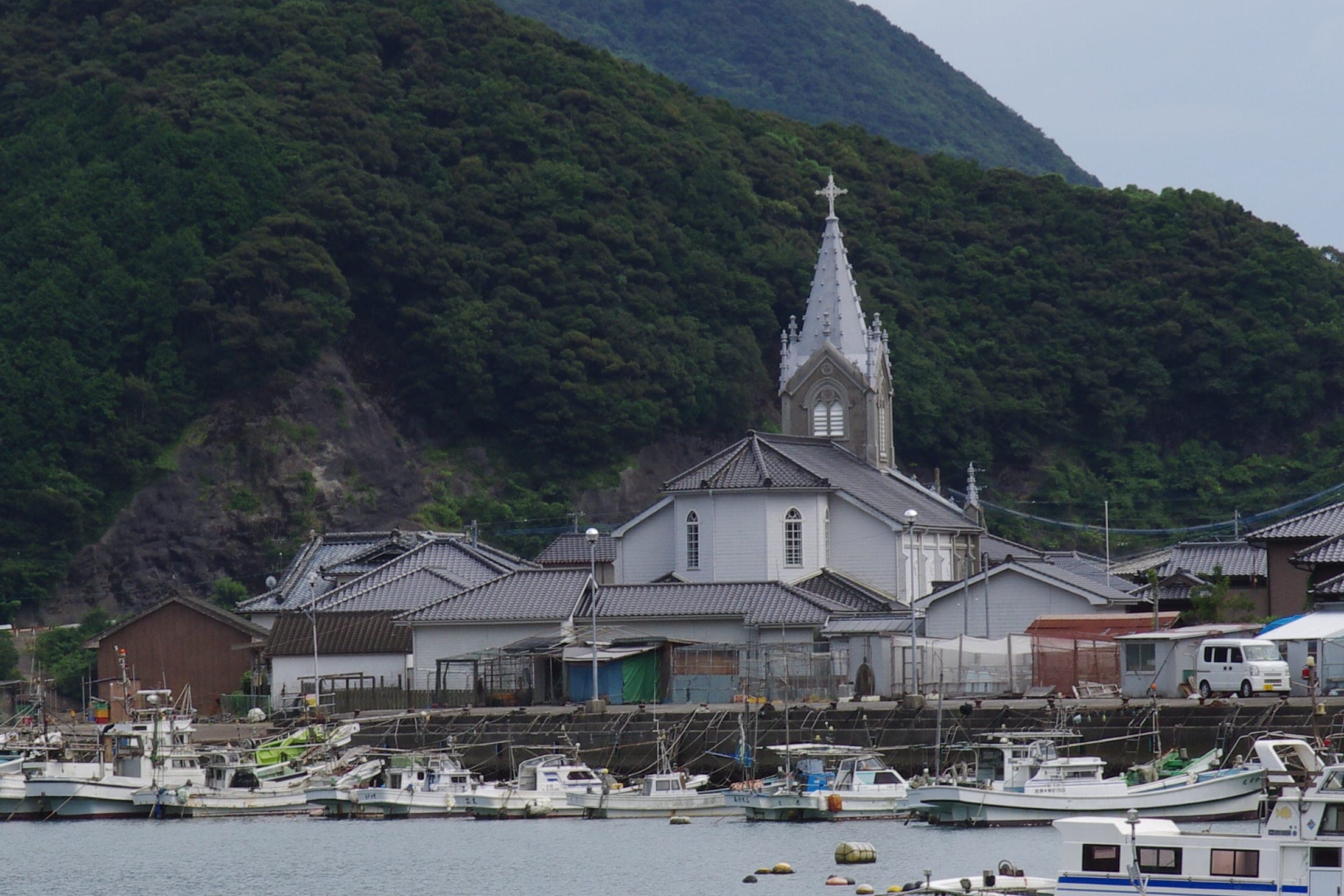 The spire of Sakitsu Church rises above fishing boats moored in the harbour of Sakitsu village.