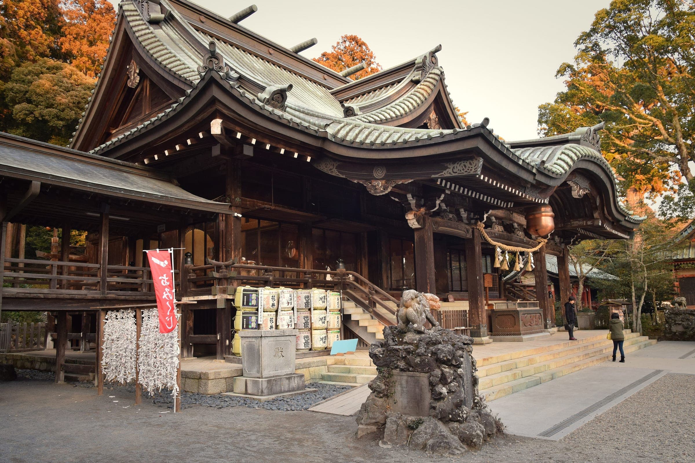 Orange leaves glow behind the curved roofs of the Mt. Tsukuba Shrine worship hall.