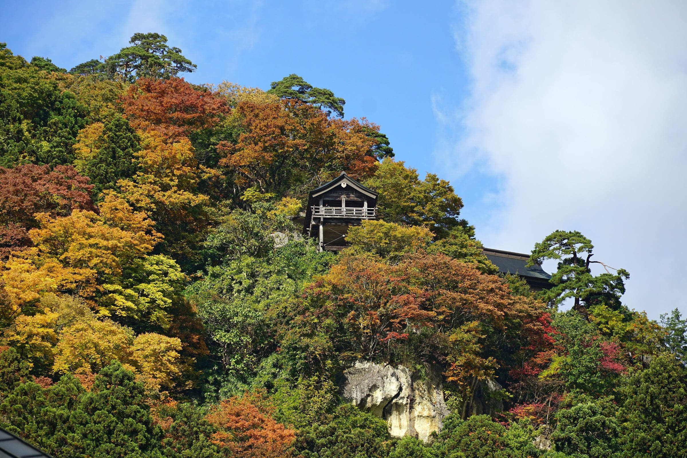 A temple hall perches on the rocky, maple-covered cliffs of Yamadera in late October.