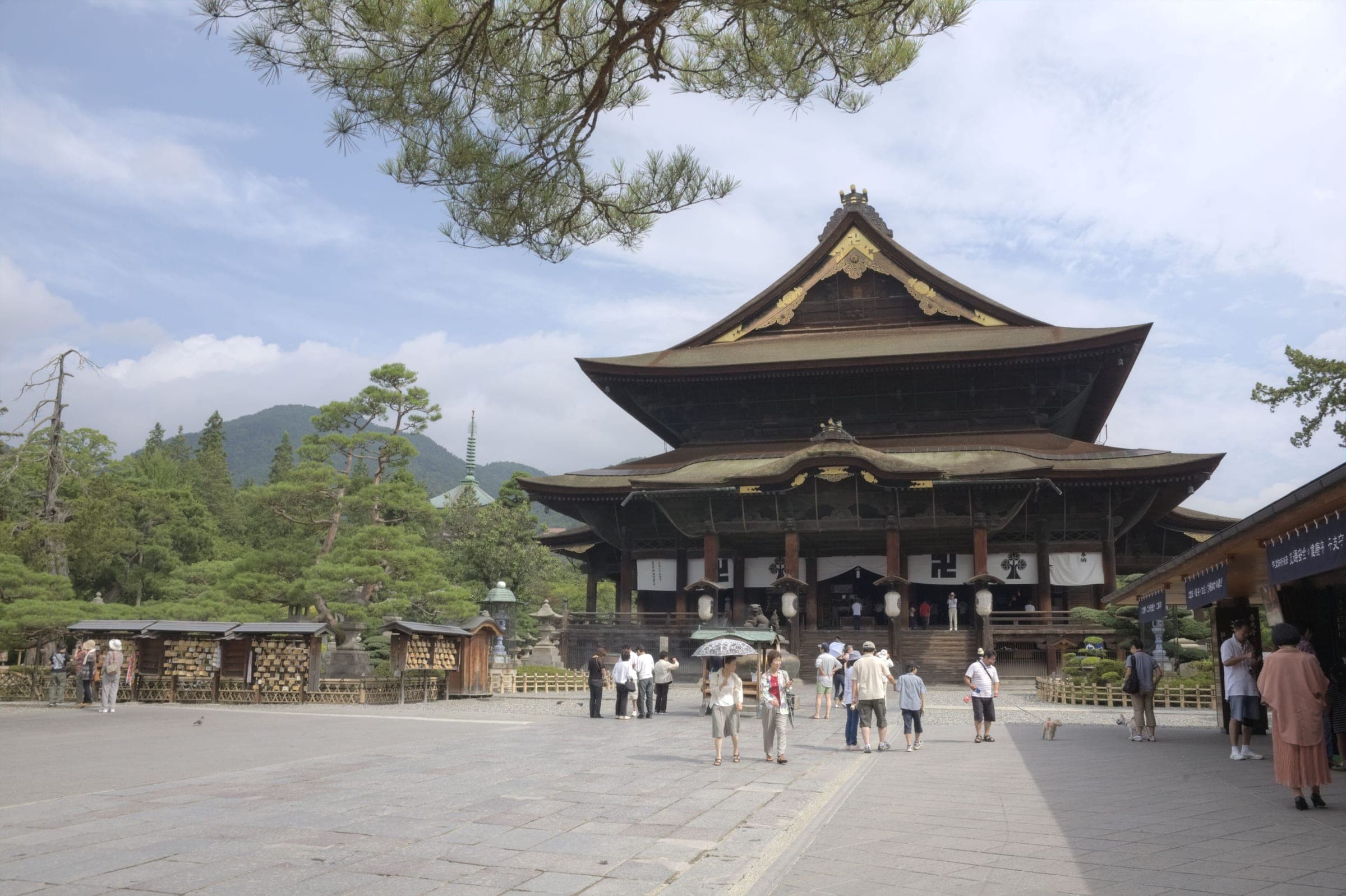 Visitors cross the stone-paved courtyard toward the great main hall of Zenko-ji in Nagano City.