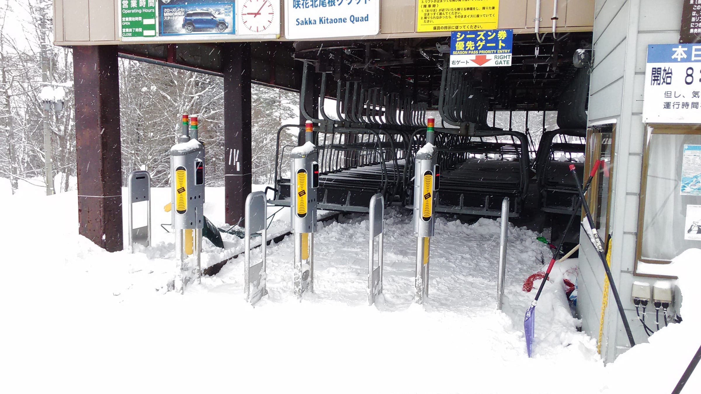 Ticket gates with Japanese signs guard the loading area of the Sakka Kitaone quad lift at Happo-one