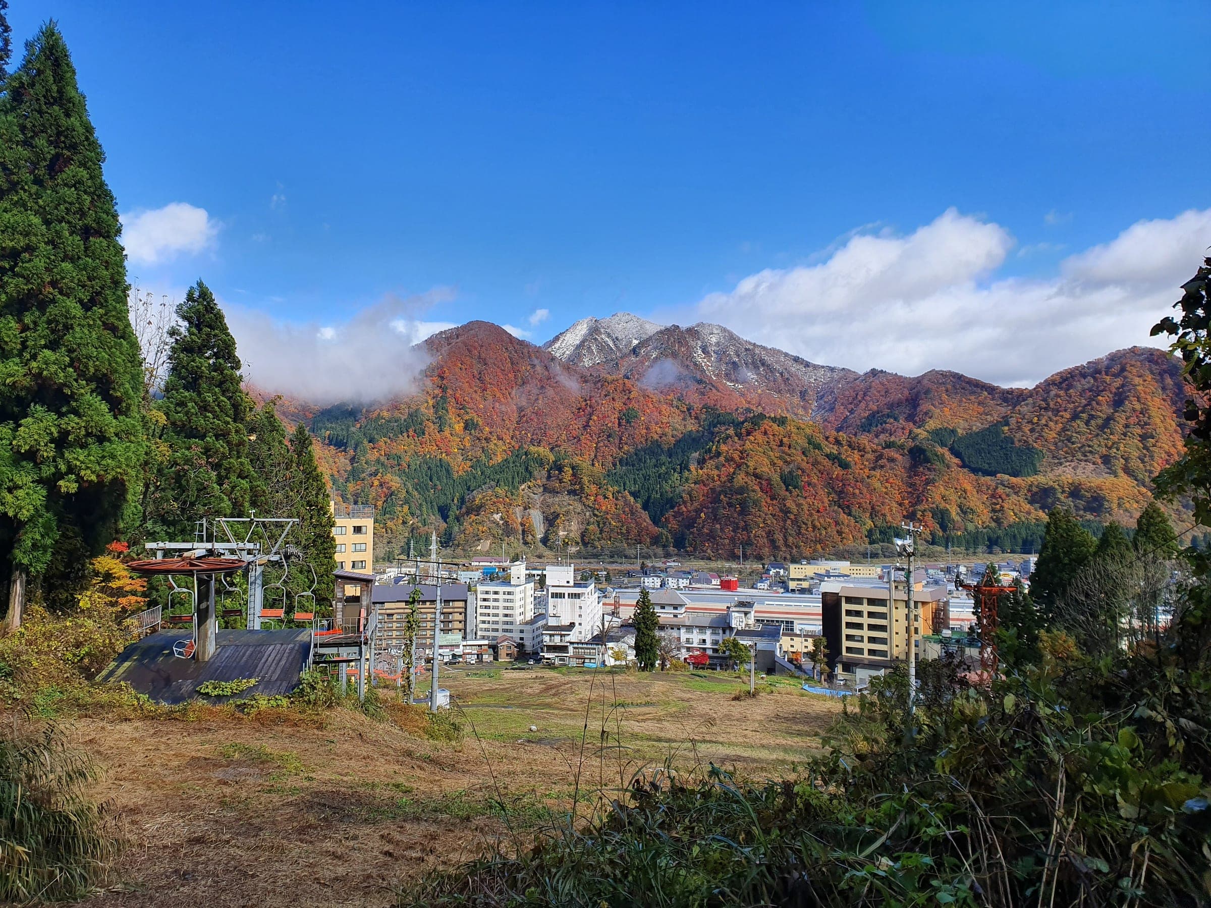 Autumn colour lights the slopes behind Echigo-Yuzawa town under a clear blue sky