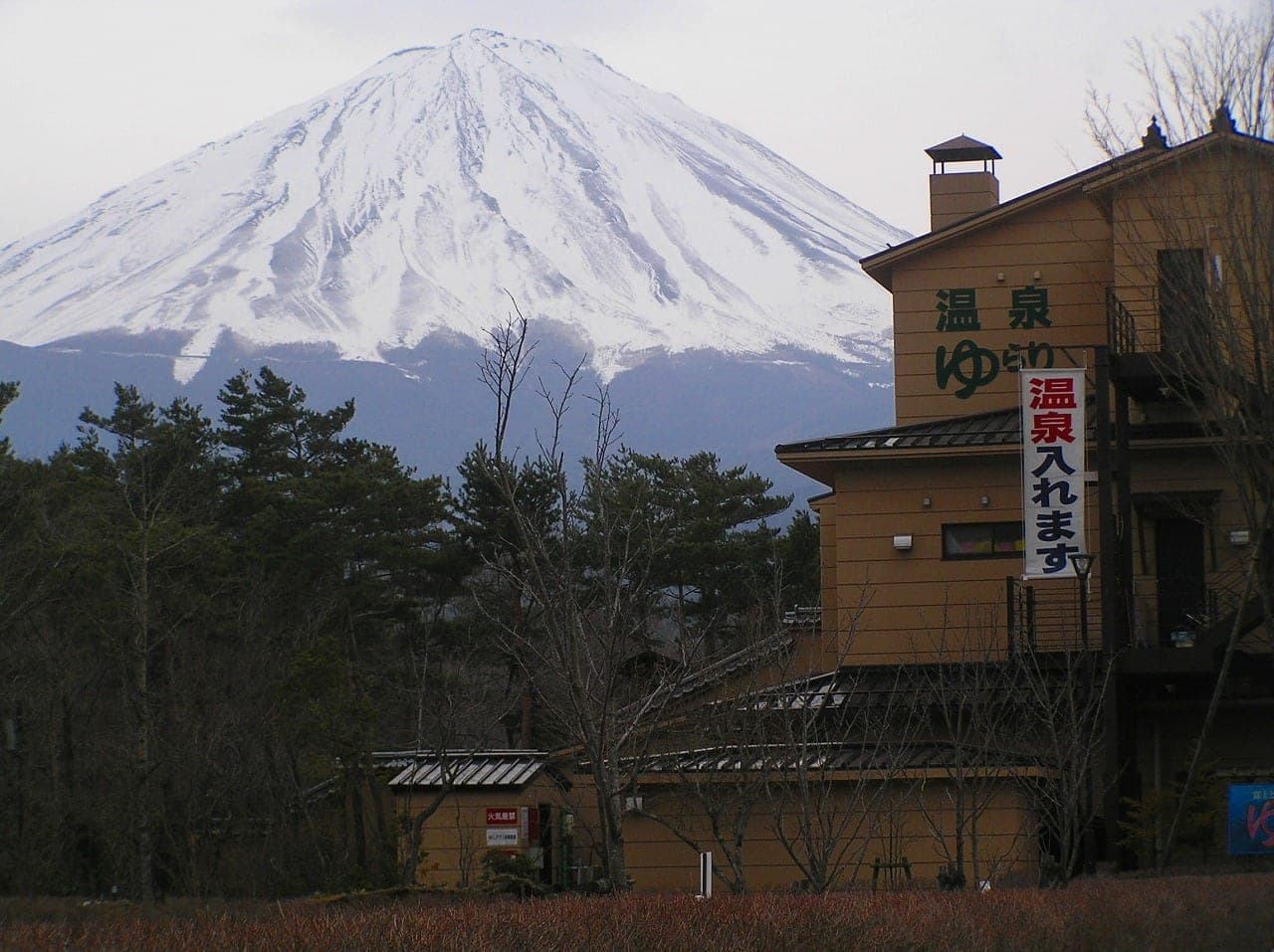 Snow-capped Mt. Fuji rises behind the Fuji-chobo no Yu Yurari bathhouse in Narusawa.