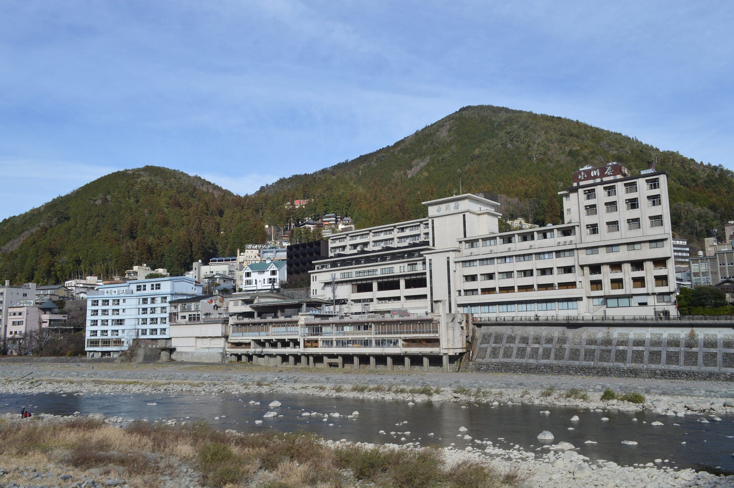 Large onsen hotels line the Hida River below a forested hill in Gero Onsen in December
