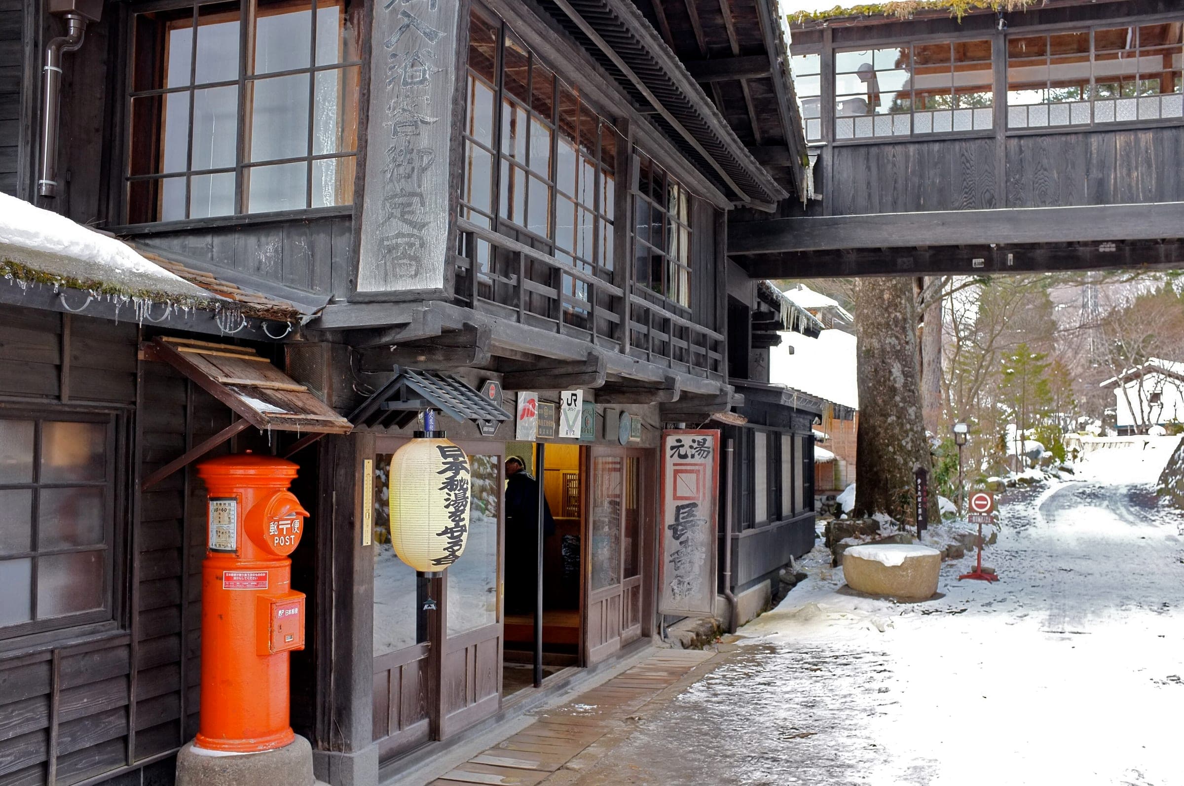 A red post box and paper lantern stand at the timber entrance of Chojukan at Hoshi Onsen