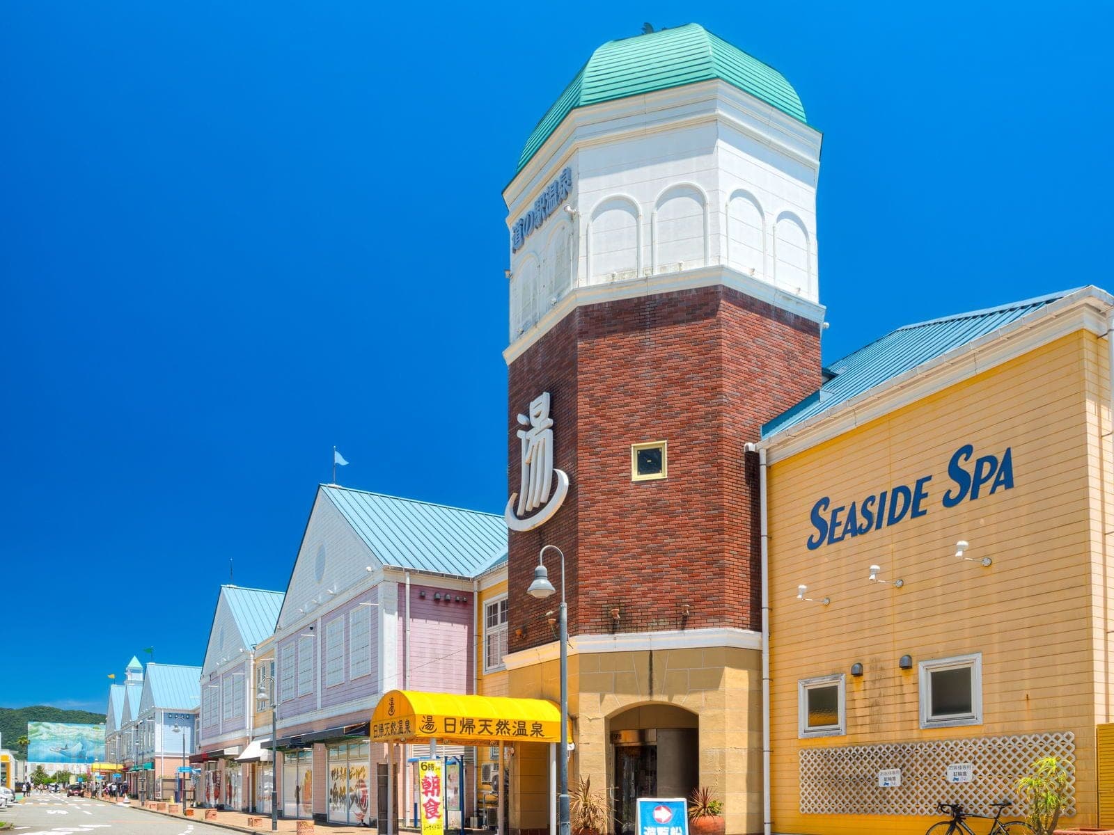 The brick tower of the Seaside Spa stands among the pastel shopfronts of Ito Marine Town.