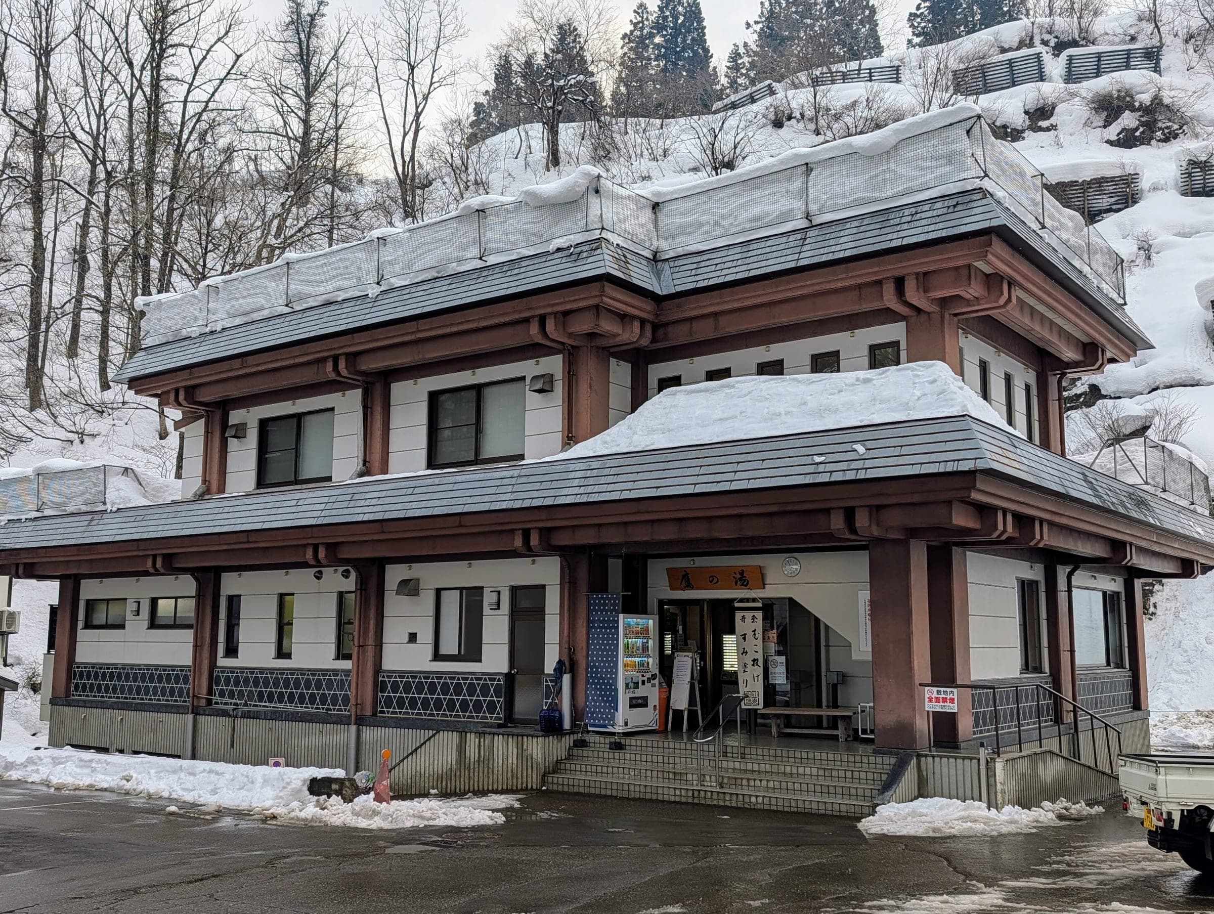 Takanoyu's tiled bathhouse stands under deep January snow at Matsunoyama Onsen
