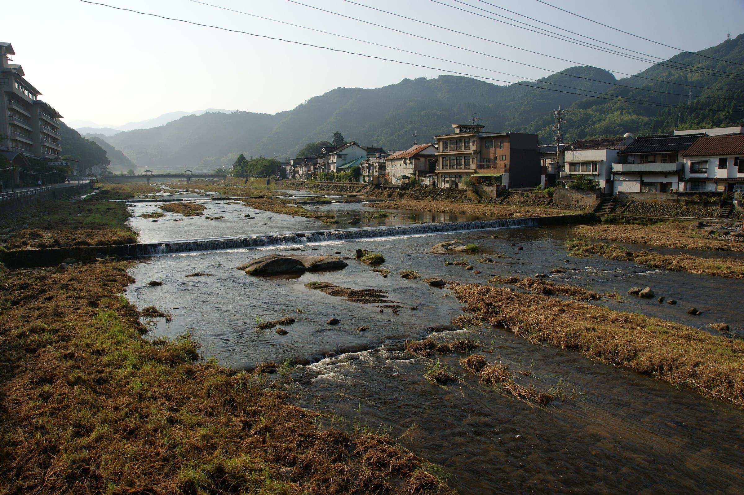 The shallow Mitoku River runs between grassy banks and the ryokan of Misasa Onsen