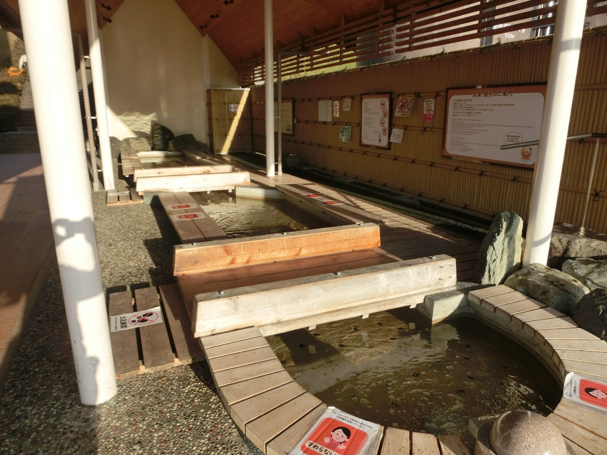Timber benches surround the shallow pools of the free foot bath in Ogoto Onsen's tourist park