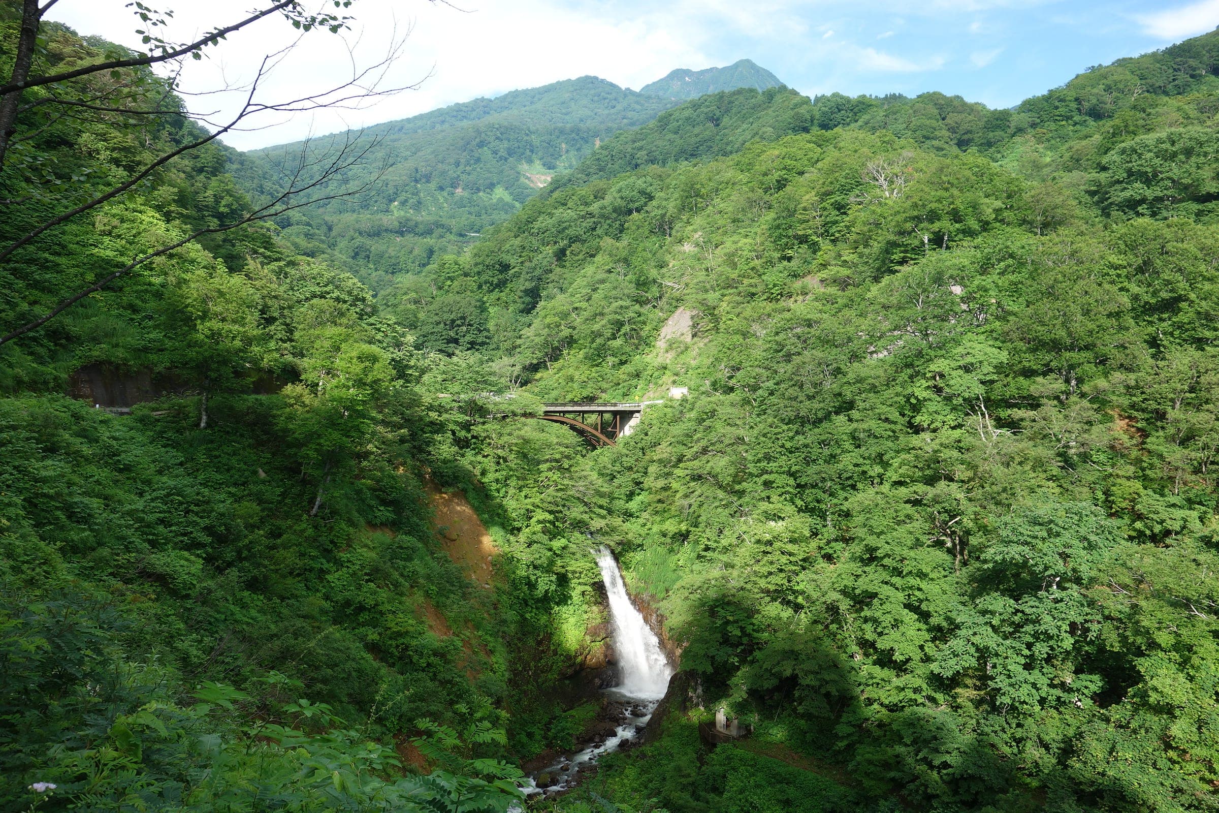 Fudo Falls drops into a forested gorge below a road bridge near Seki Onsen in July