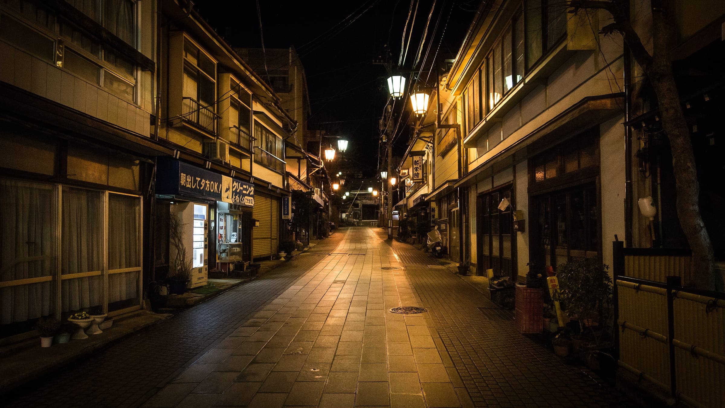 Lamps light the empty stone-paved main street of Shibu Onsen at night.