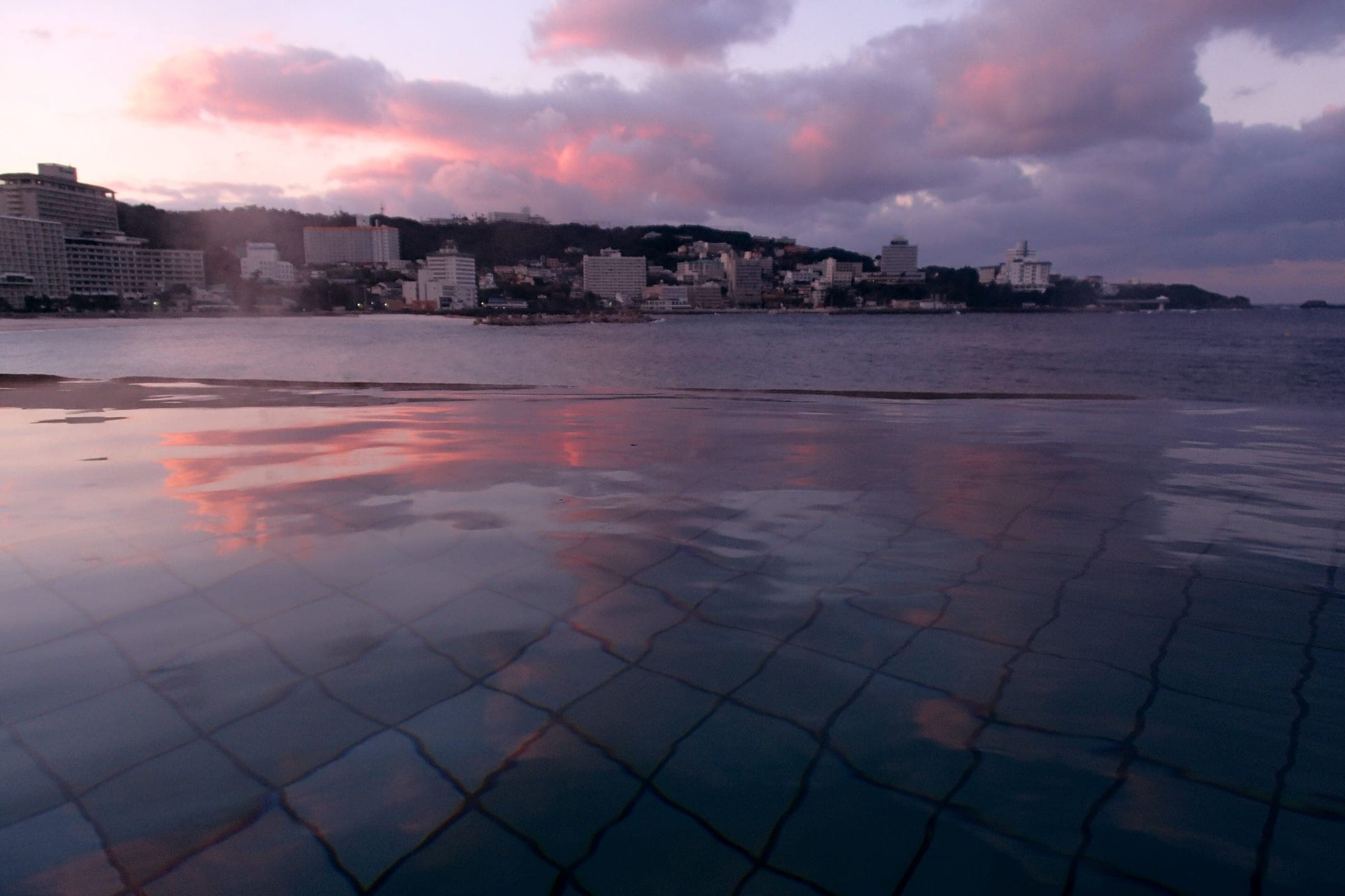 Hotels of Shirahama Onsen line the bay under a pink December sky at dusk