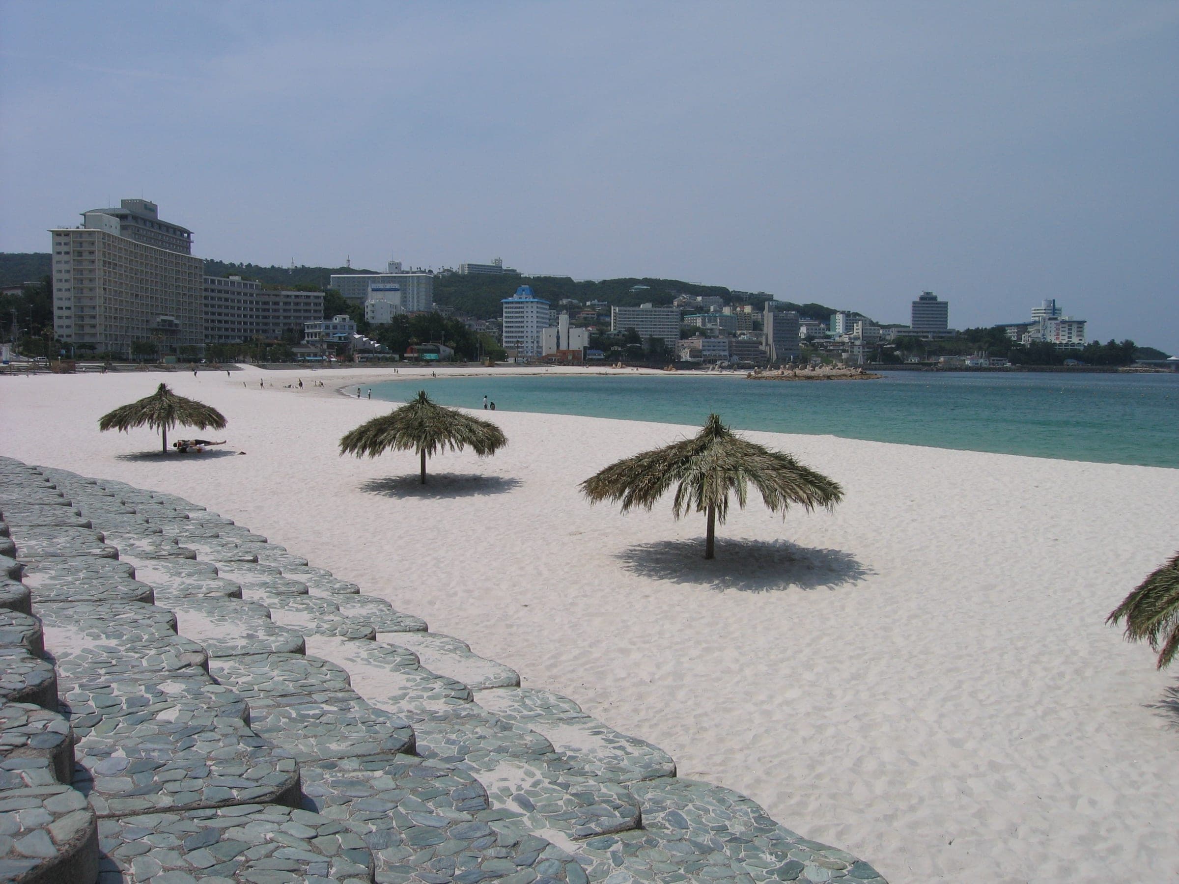 Thatched parasols stand on the white sand of Shirarahama beach in Shirahama