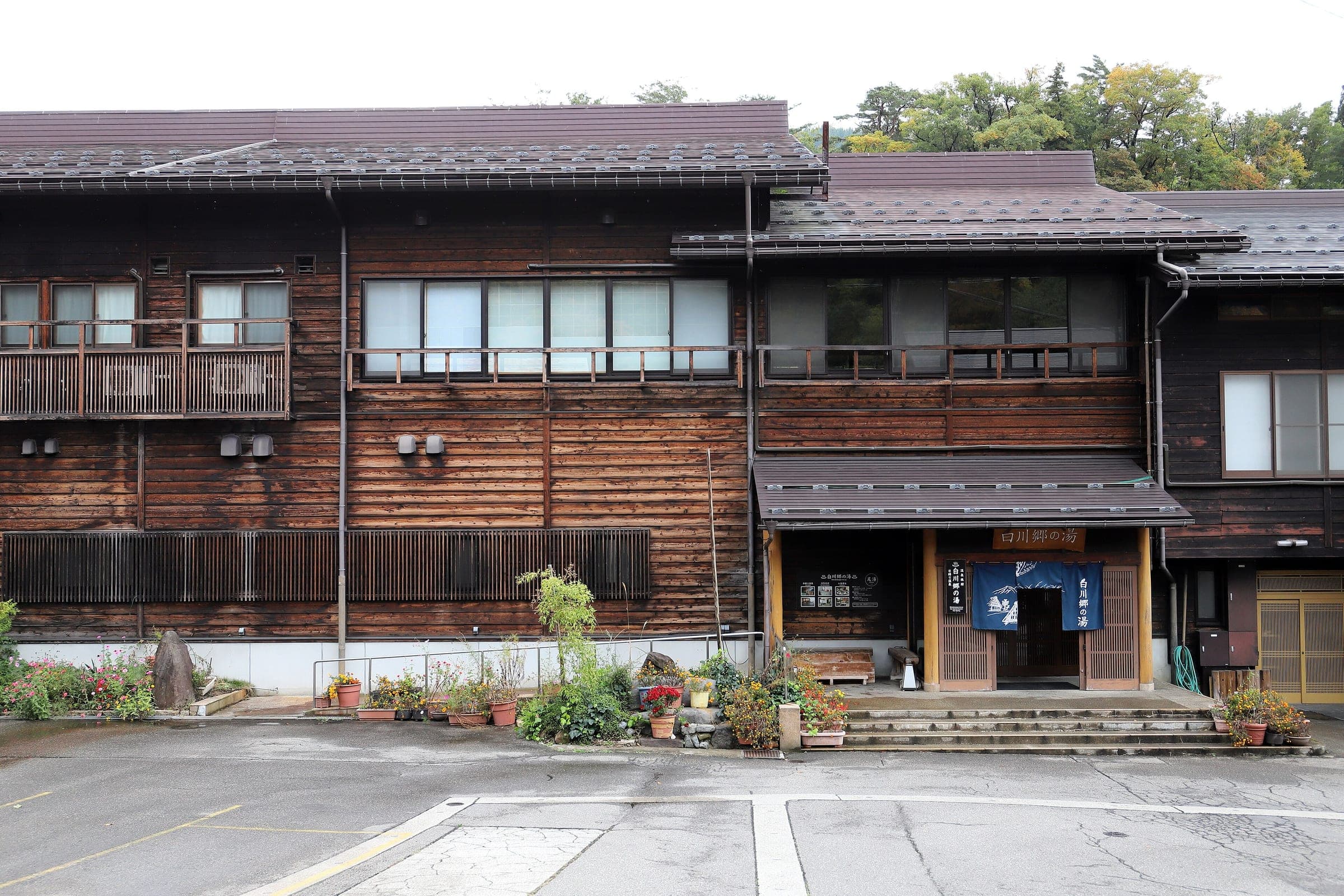 The wooden two-storey building of Shirakawago no Yu stands beside its car park in Ogimachi