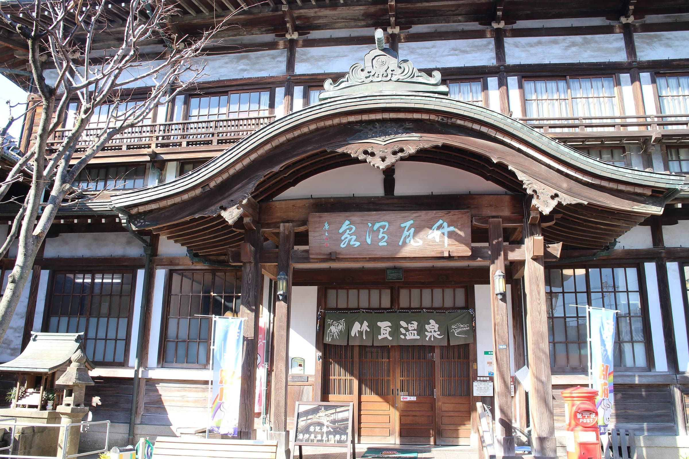 A curved karahafu gable crowns the wooden entrance of Takegawara Onsen in Beppu on a winter day.