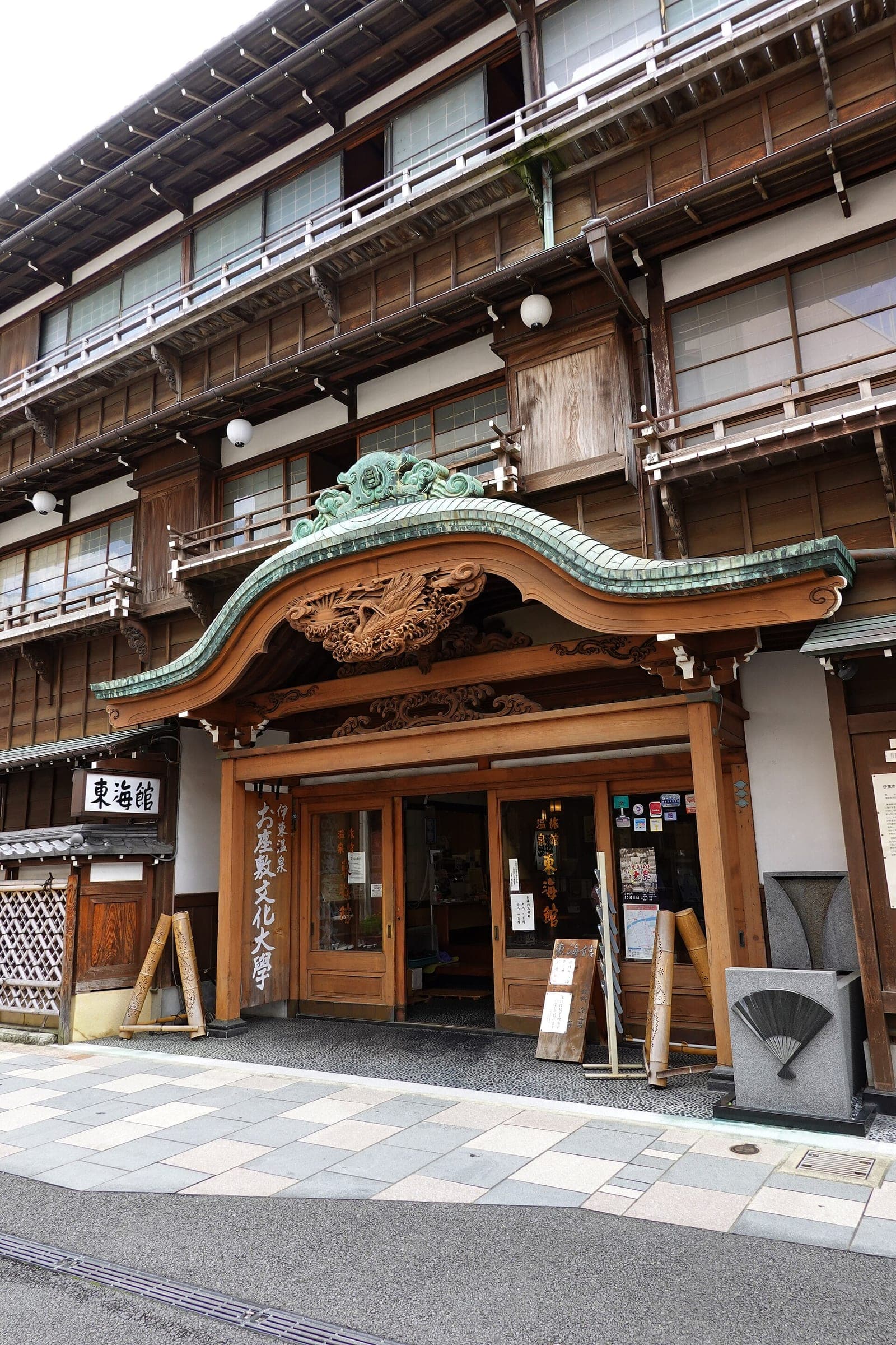 A carved wooden gable shelters the front entrance of the Tokaikan in Ito.