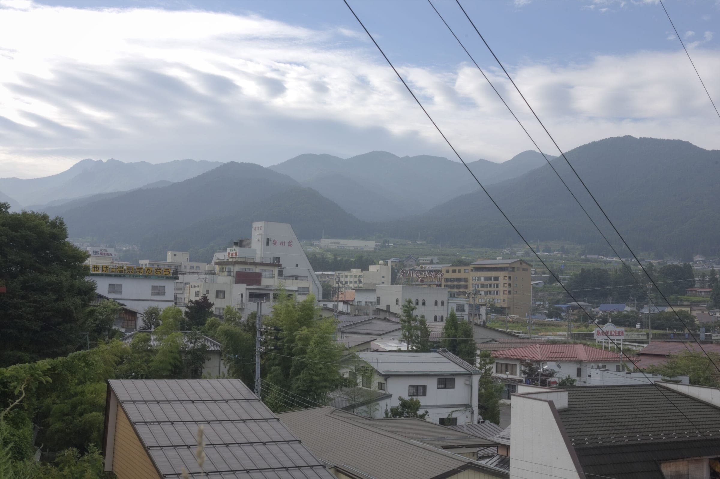 The rooftops of Yudanaka Onsen spread below the forested mountains of Shiga Kogen.