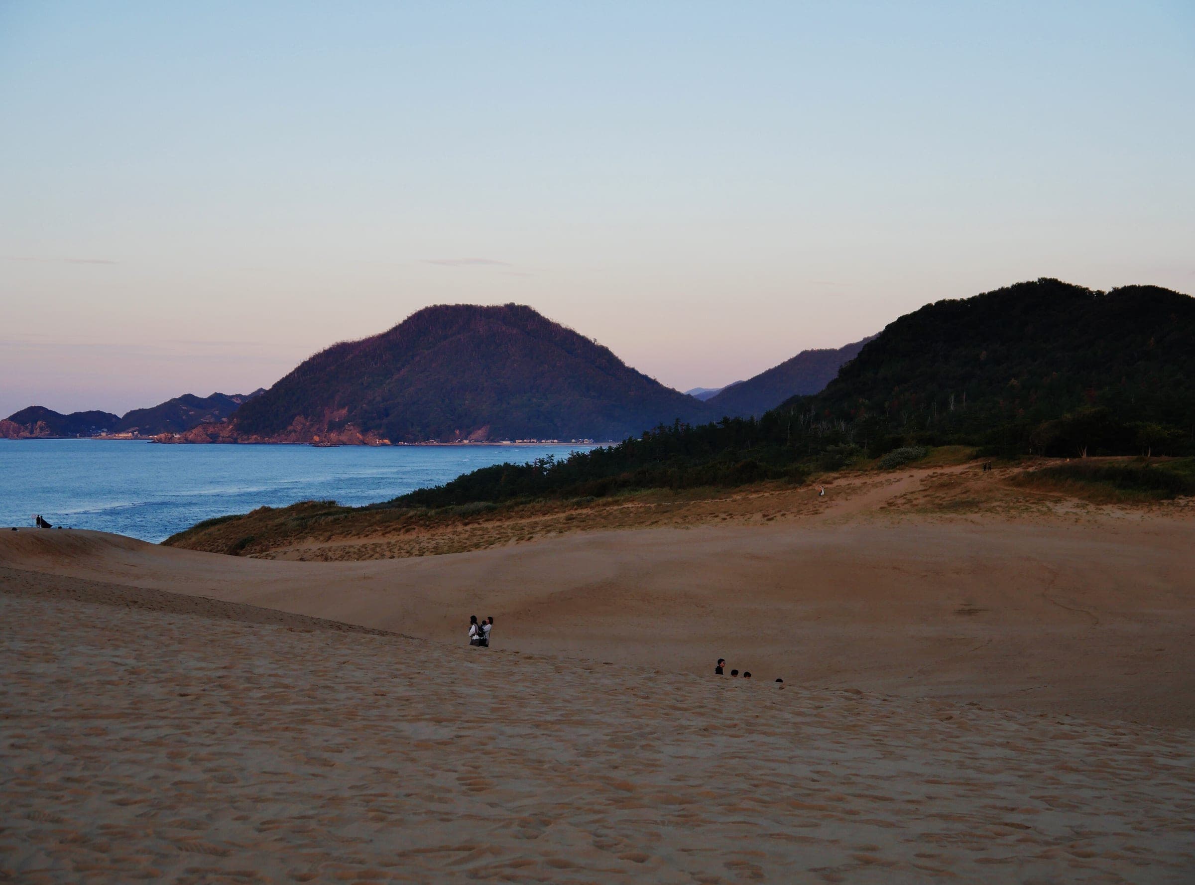 Dusk falls over the Tottori Sand Dunes with the Sea of Japan and coastal hills beyond
