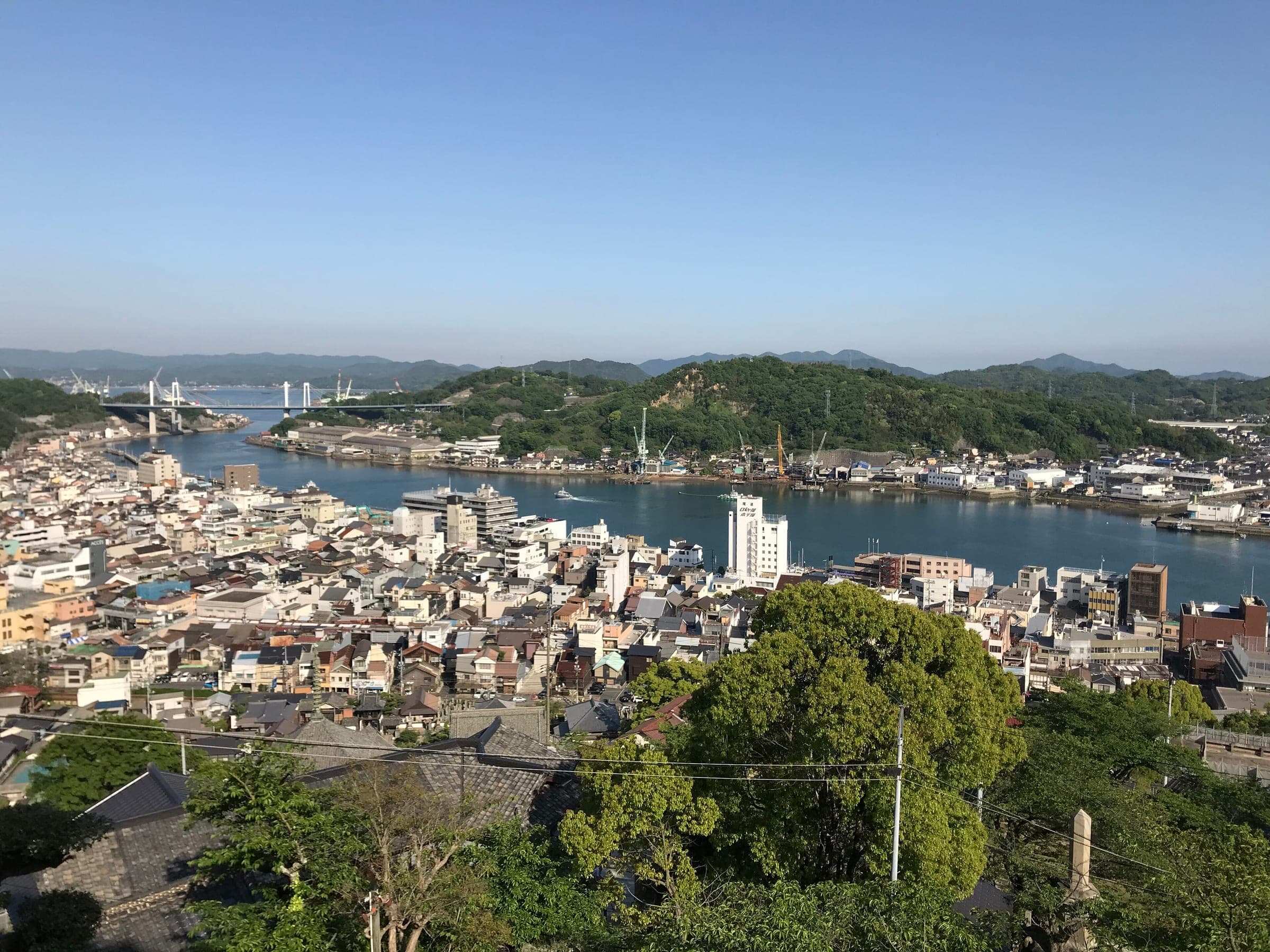 Onomichi's rooftops run down to the Onomichi Channel with Mukaishima and the Onomichi bridges beyond