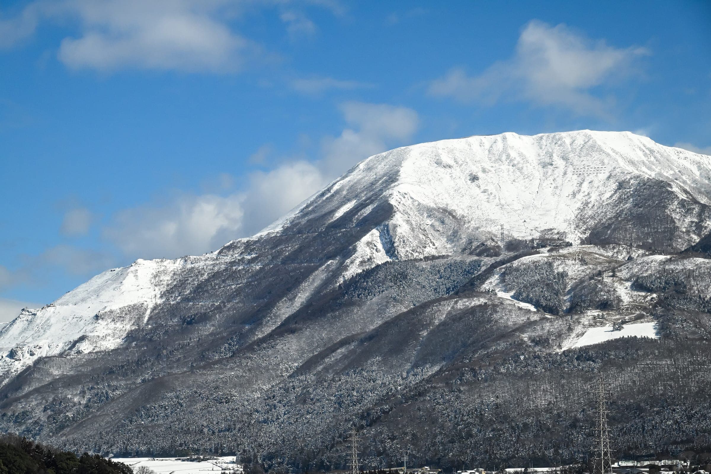 Snow covers the summit of Mount Ibuki above the forested foothills of Maibara in early March