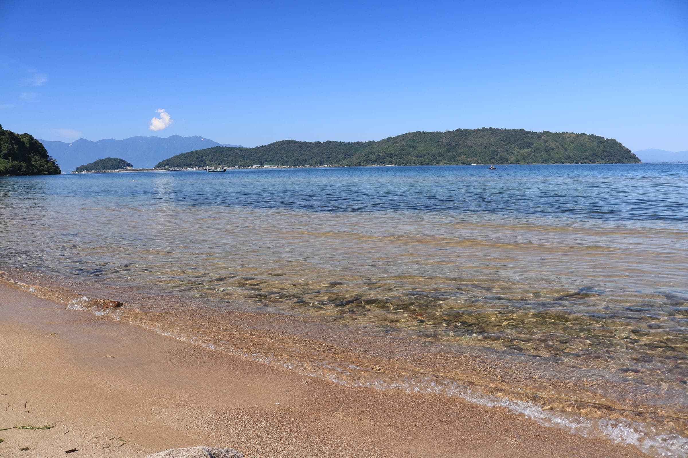 Clear water laps the sand at Miyagahama in Omihachiman with Okishima island across Lake Biwa