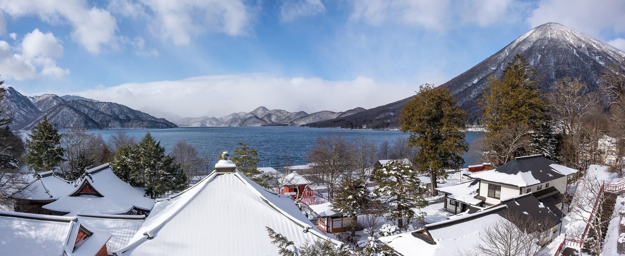 Snow lies on the roofs of Chuzenji above Lake Chuzenji with Mount Nantai rising beyond in December