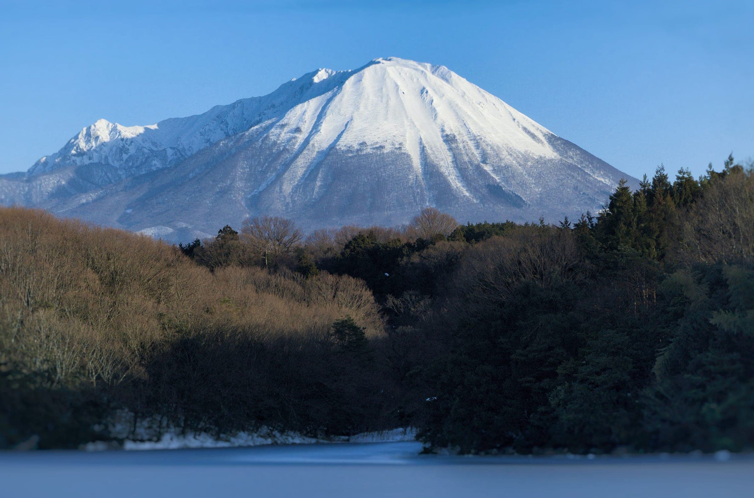 Mount Daisen shows its snowy northwest side above a reservoir on a late January afternoon