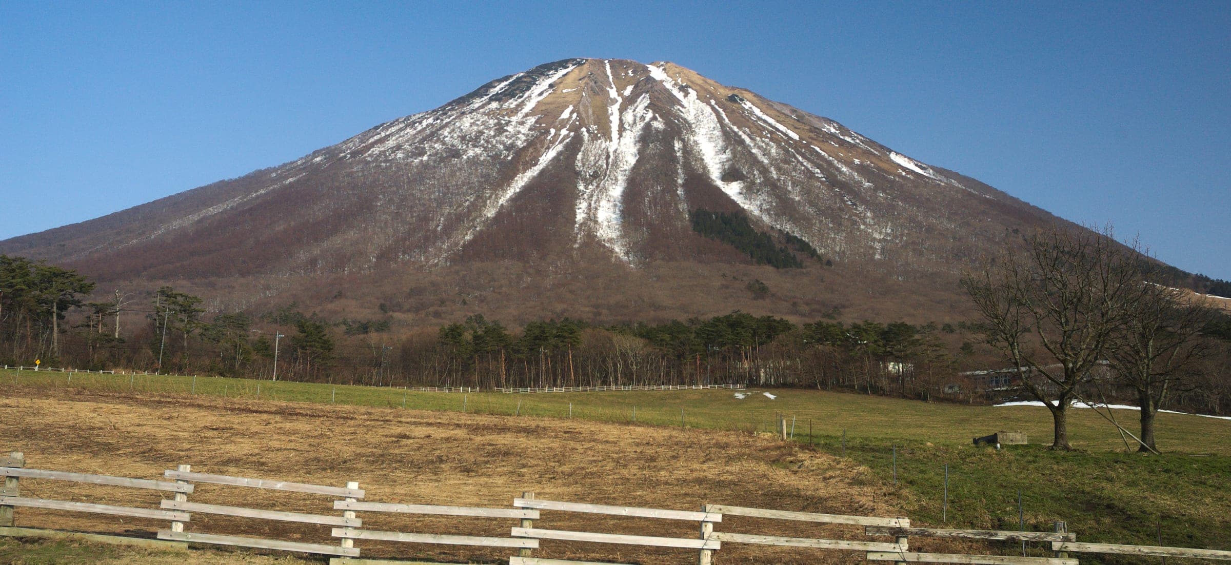 Snow lingers in the gullies of Mount Daisen above open pasture on its western flank in early March