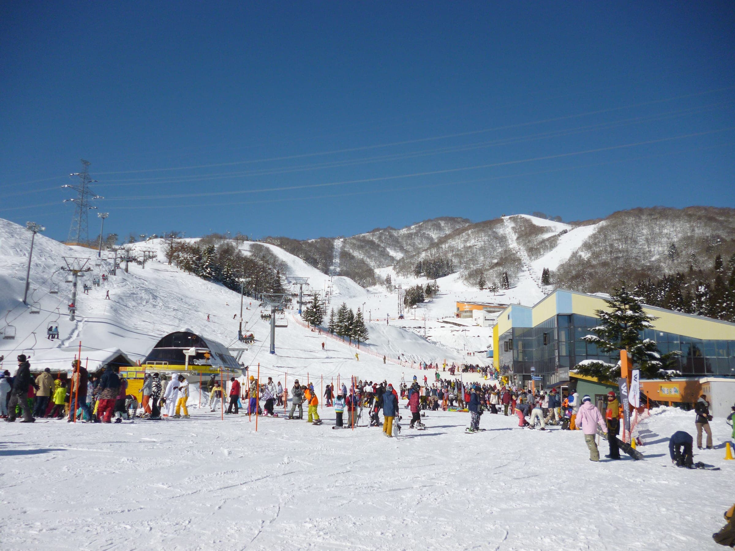 Skiers and snowboarders gather by the lifts and base lodge at Dynaland on a clear January day