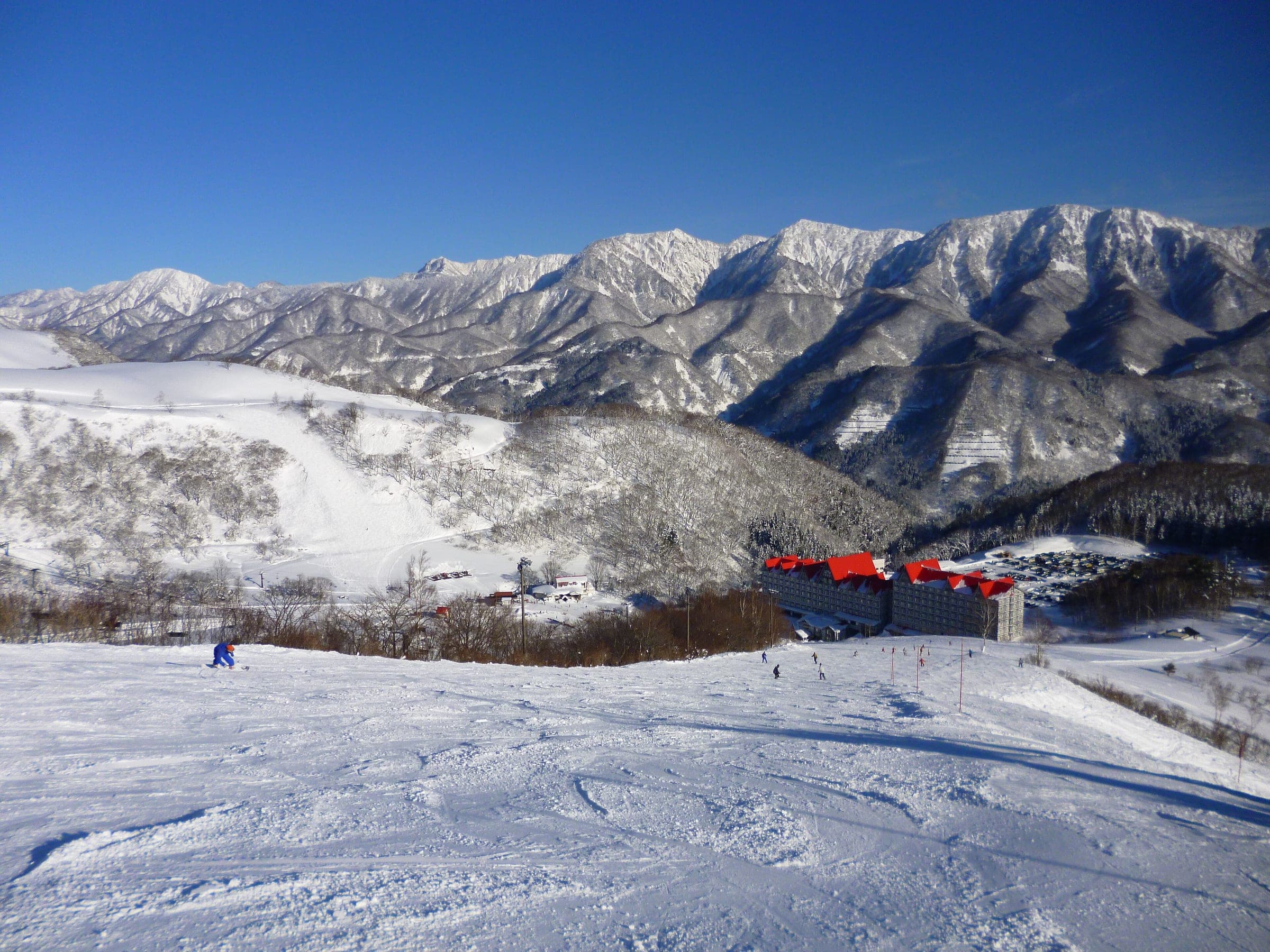 A groomed run at Hakuba Cortina looks down on the red roofs of Hotel Green Plaza under snowy peaks