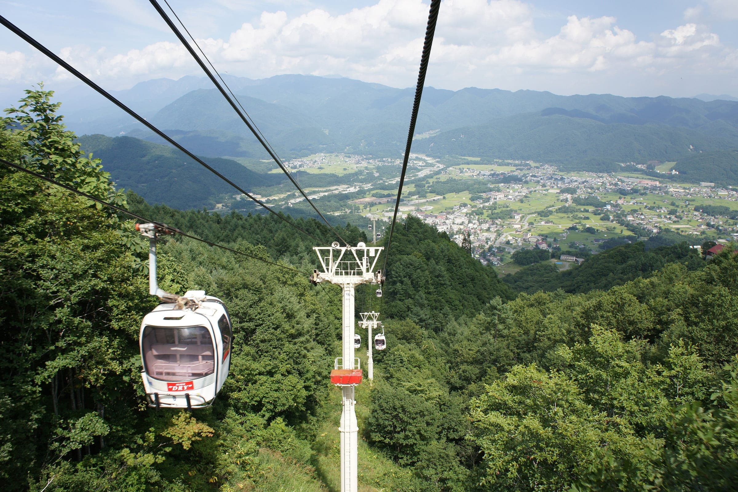 The Adam gondola climbs Hakuba Happo-one in summer with the Hakuba valley spread out below