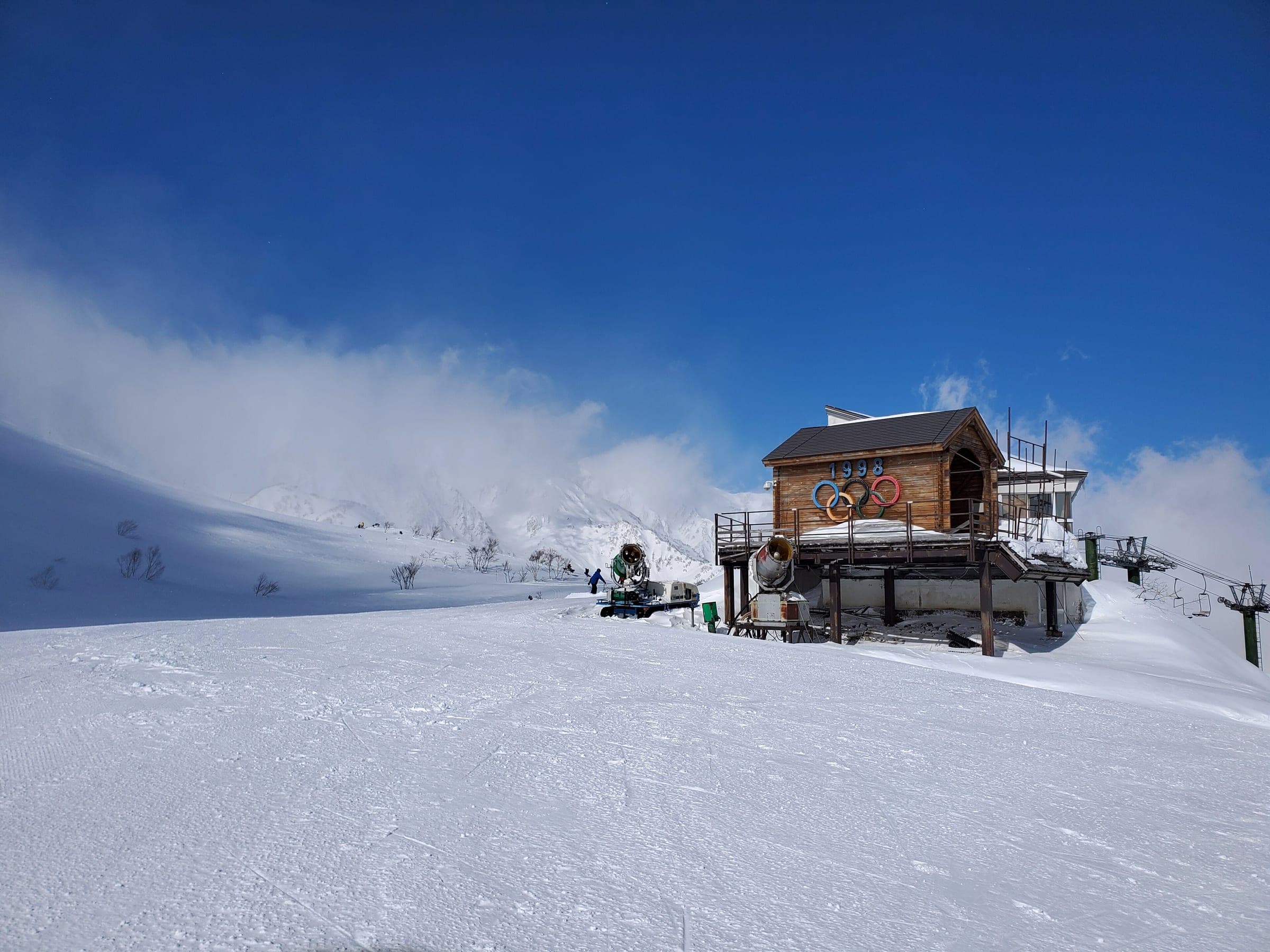 A wooden lift hut with Olympic rings stands on the groomed upper slopes of Hakuba Happo-one