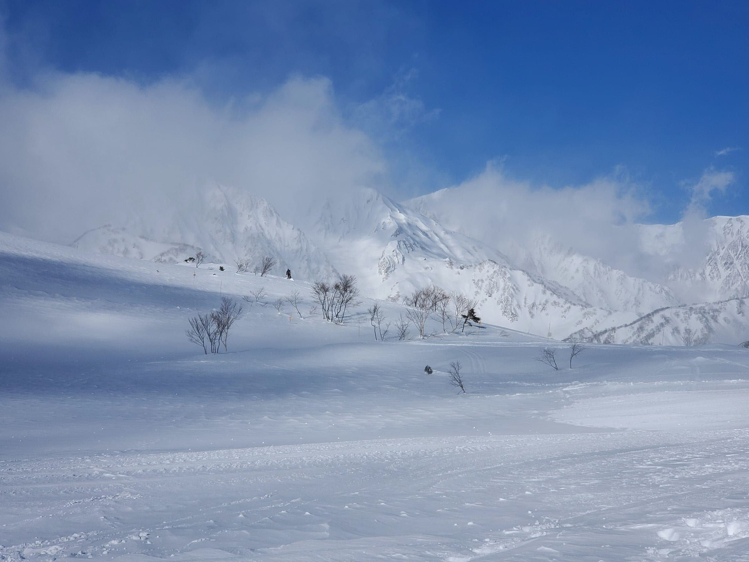 Riders cross the upper slopes of Hakuba Happo-one as cloud lifts off the Northern Alps