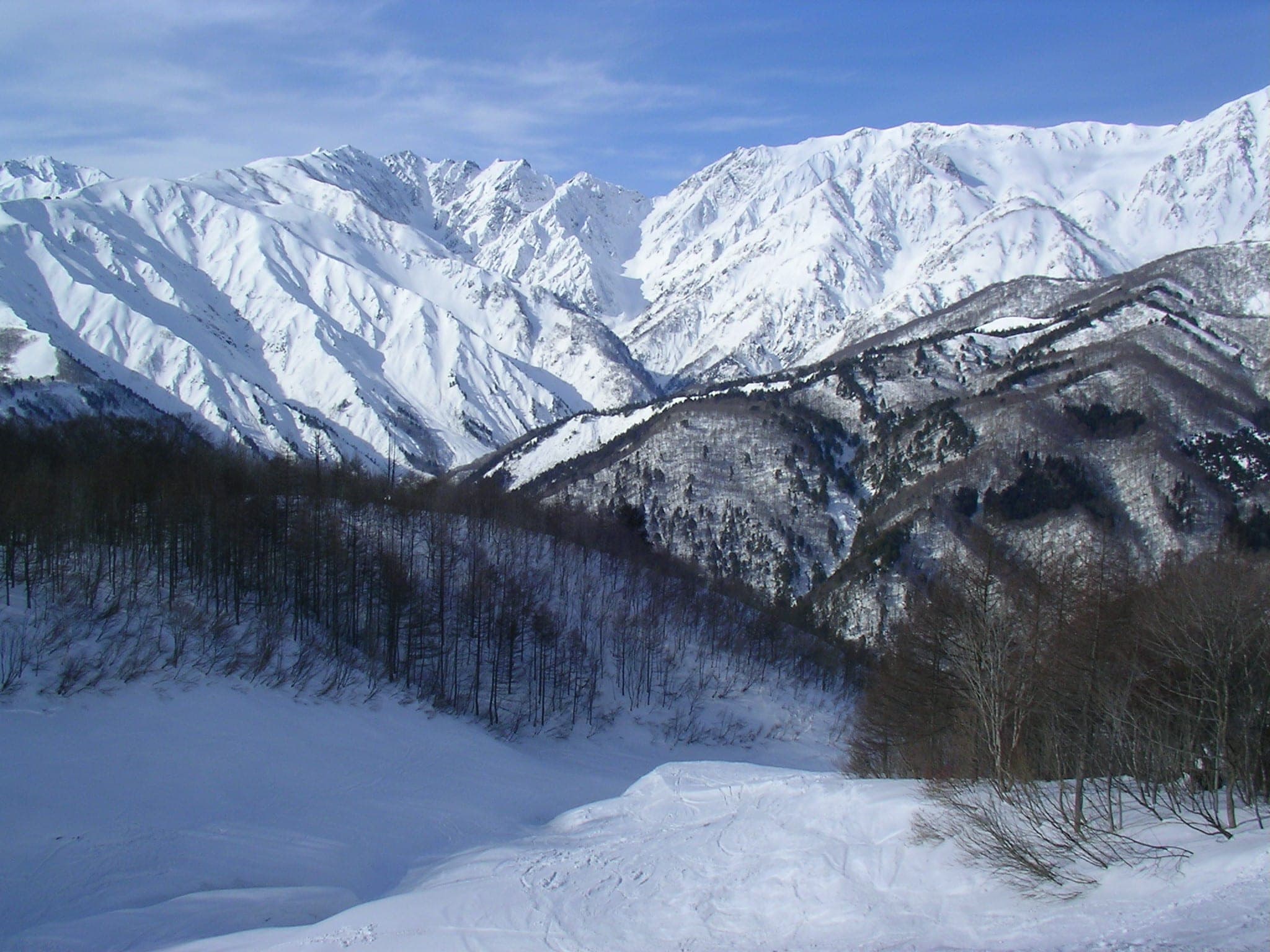 Mount Karamatsu stands deep in snow beyond a run at Hakuba Iwatake