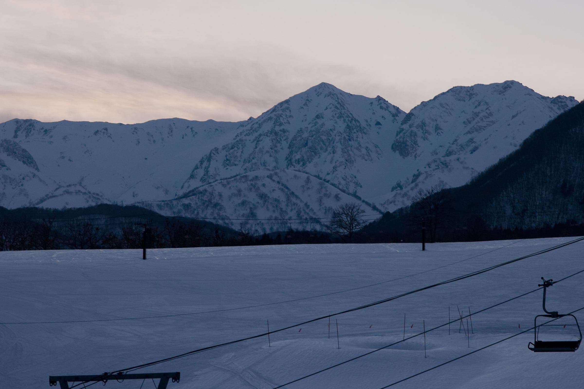 Mount Hakuba Yarigatake catches the last light above an empty Tsugaike chairlift at dusk