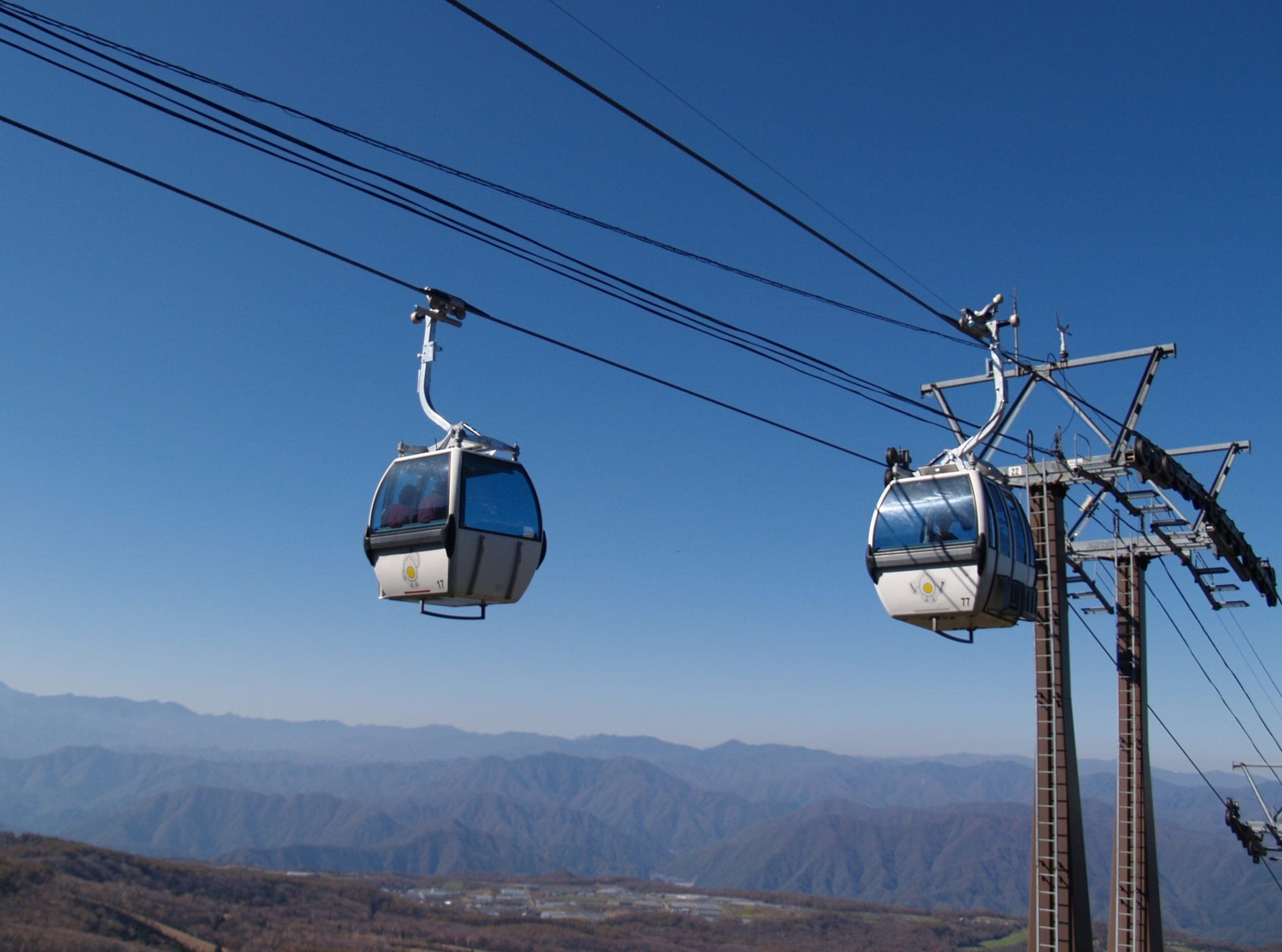 Gondola cabins at Hunter Mountain Shiobara pass a tower against a clear October sky