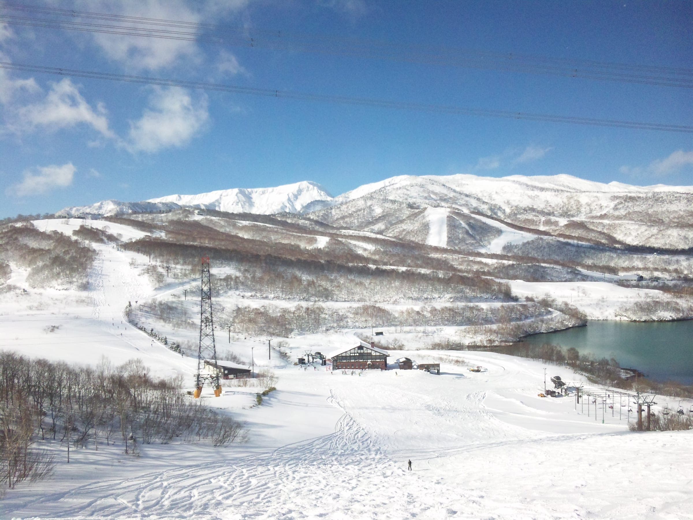 Mount Naeba and Kaguragamine stand white above the lower slopes and lake at Kagura