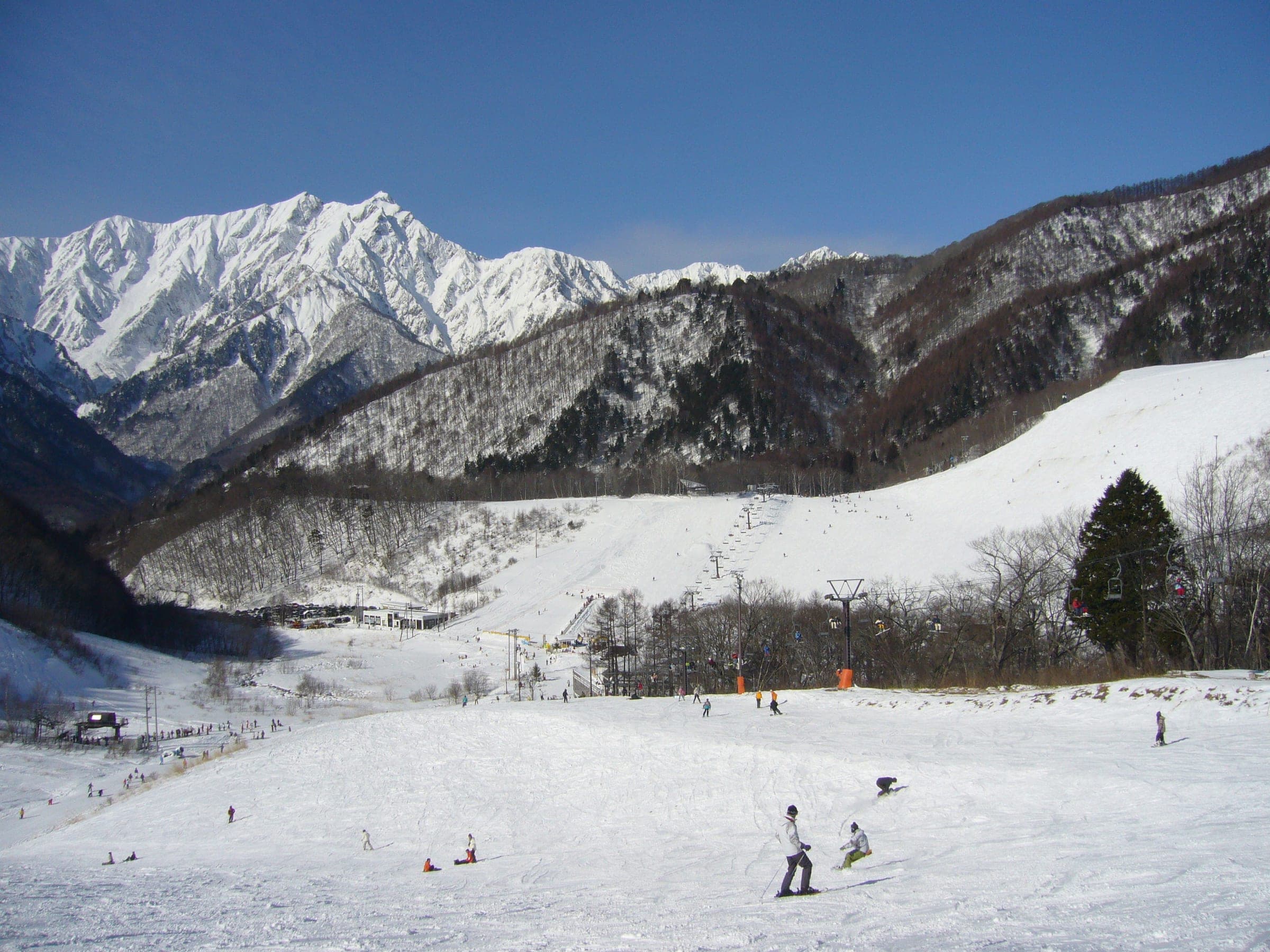 Skiers and snowboarders share the lower slopes of Kashimayari below the white wall of Mount Kashimayari