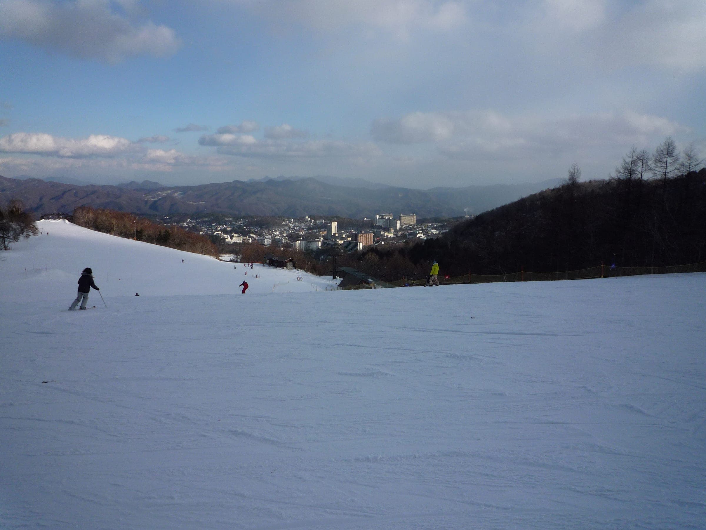 Skiers on a broad slope at Kusatsu Onsen Ski Resort above the hot-spring town in February