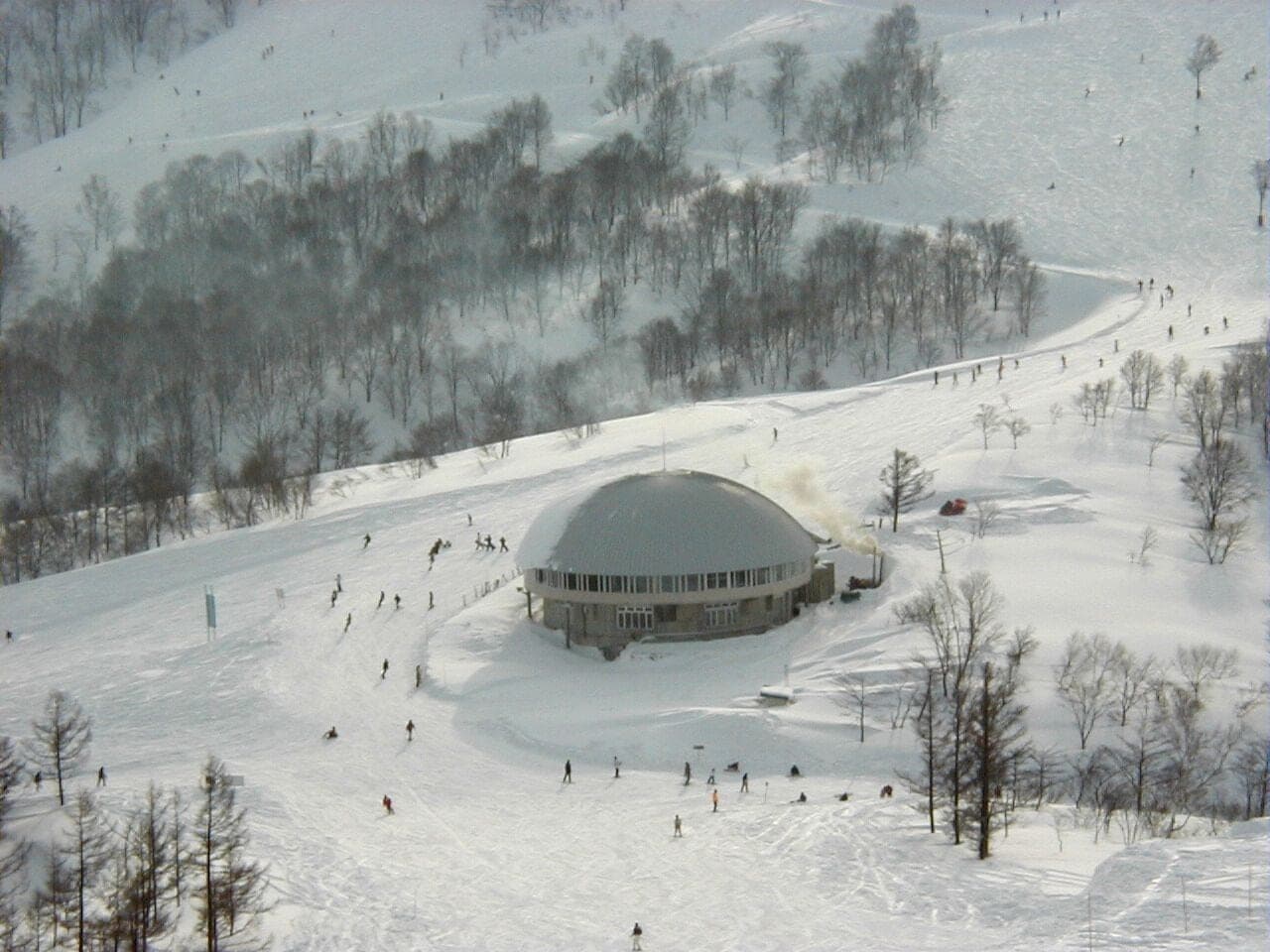 Skiers stream past the round dome lodge on the open slopes of Maiko Snow Resort
