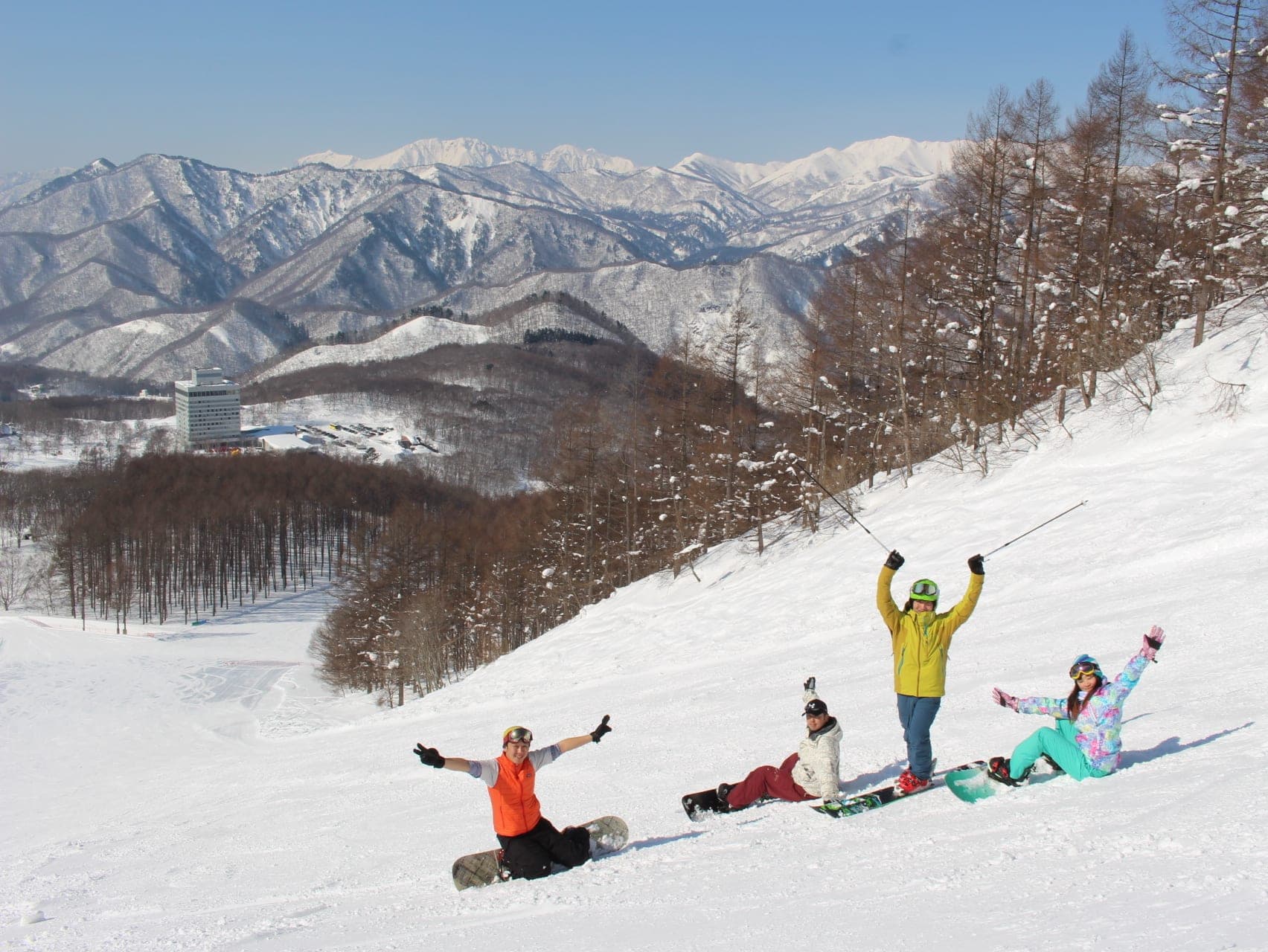 Snowboarders rest on a groomed run at Minakami Kogen with the Gunma ranges white behind them