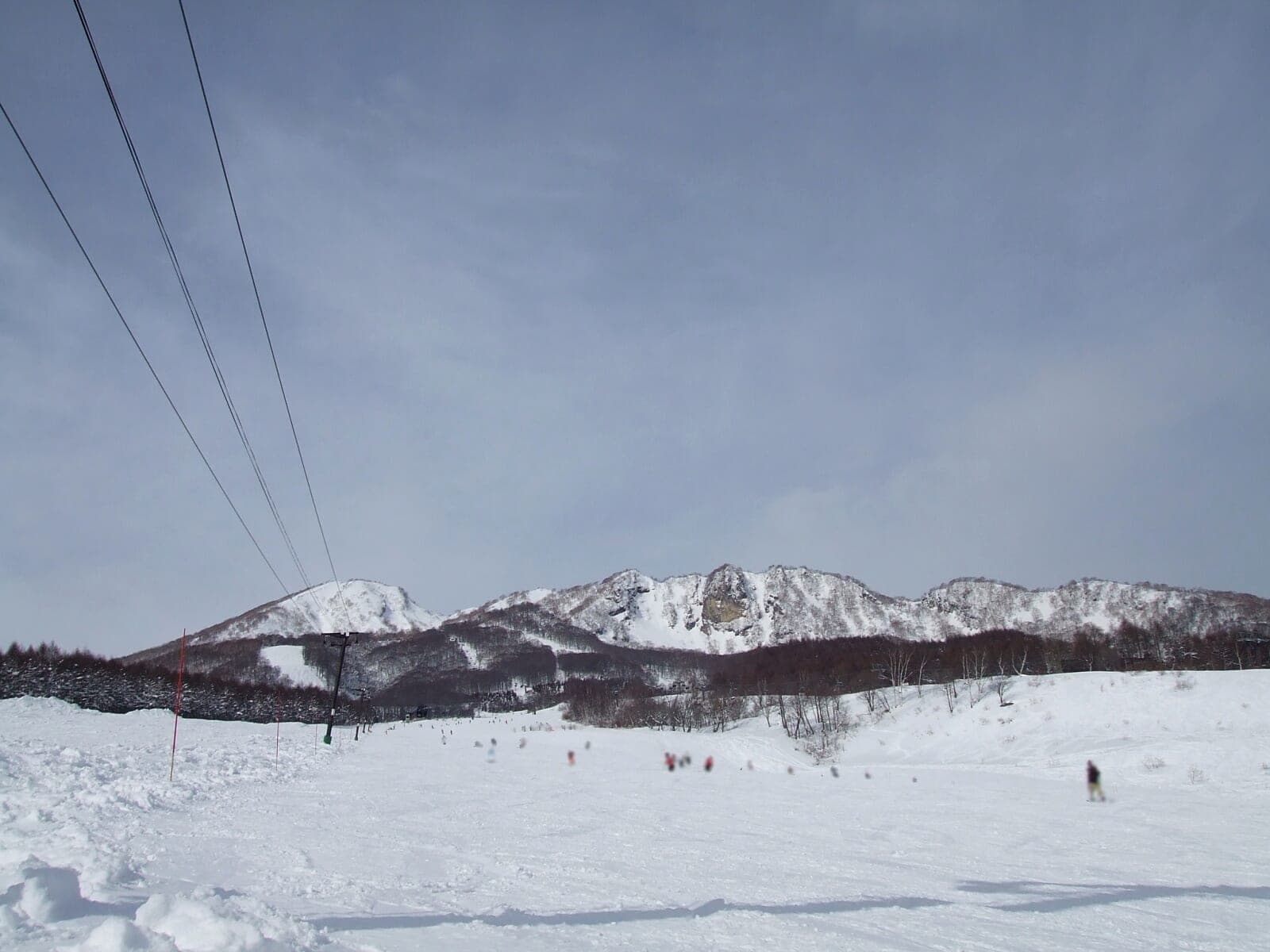 Skiers dot the broad Panorama slope at Myoko Suginohara below the rocky Myoko ridge